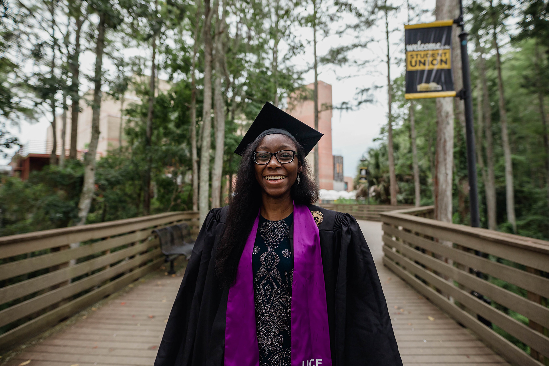 Lynette standing on bridge in grad cap and gown