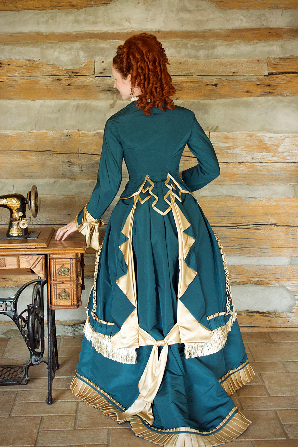 1876 Silk Faille Gown: This is inspired by styles of the end of the Early Bustle Era. Careful pleating of silk charmeuse is added to the silk faille skirt, overskirt and bodice. The bodice is fully boned to support the silhouette. Trim and internal finishing is completed with tiny hand stitching. As carefully constructed inside as out. Enquire for Couture pricing.