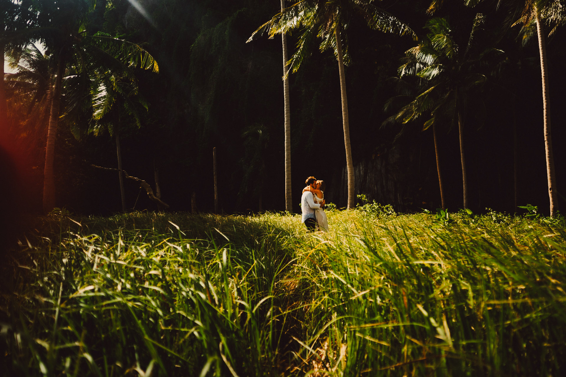 Moody couple portraits with a tropical vibe against a shadowy limestone cliff, palm trees and knee-high cogon grass, Pinagbuyutan Island, El Nido, Palawan, Philippines, Southeast Asia, December 2019, Sony A7III.
