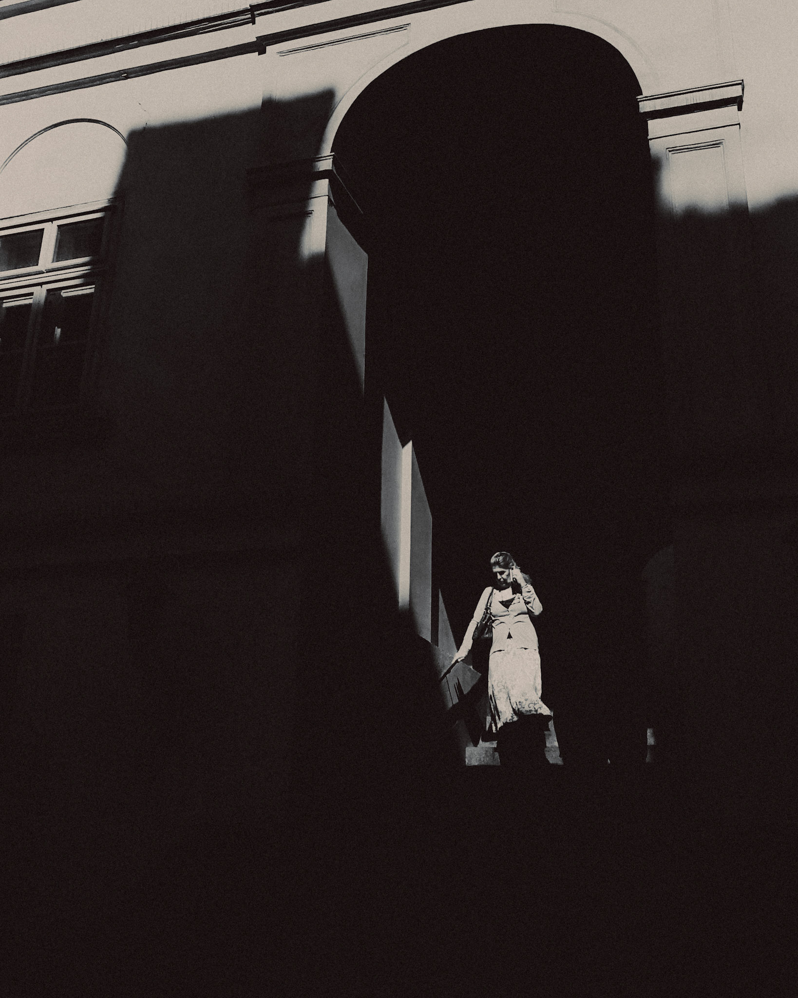 A woman in a shadowy archway, in black and white, Vienna, Austria, August 2017, Huawei Mate 9 Pro.