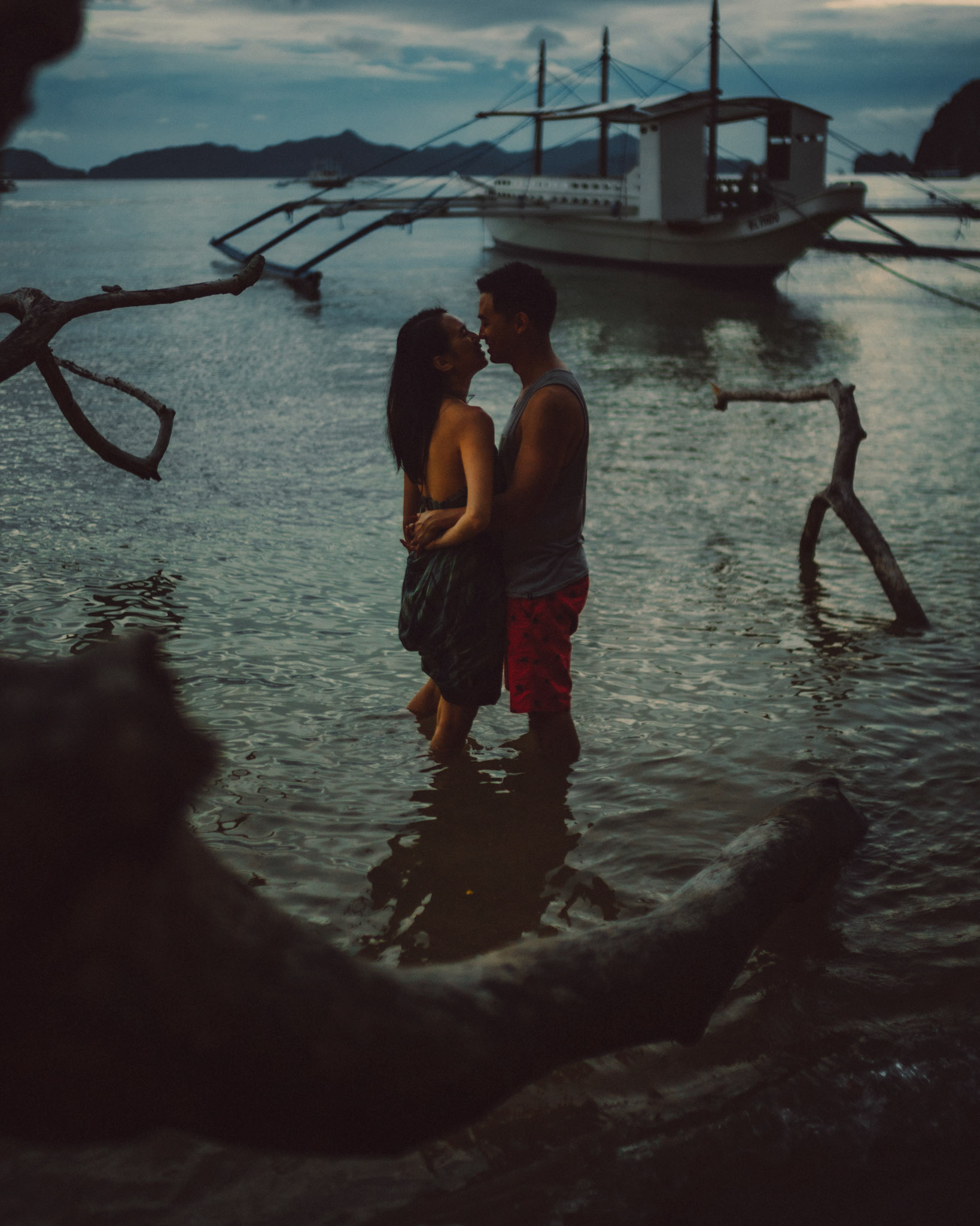 Moody blue hour couple photos with an outrigger boat and a fallen tree, from George and Allie's honeymoon portrait shoot, Corong-Corong Beach, El Nido, Palawan, Philippines, Southeast Asia, December 2018, Sony A7III