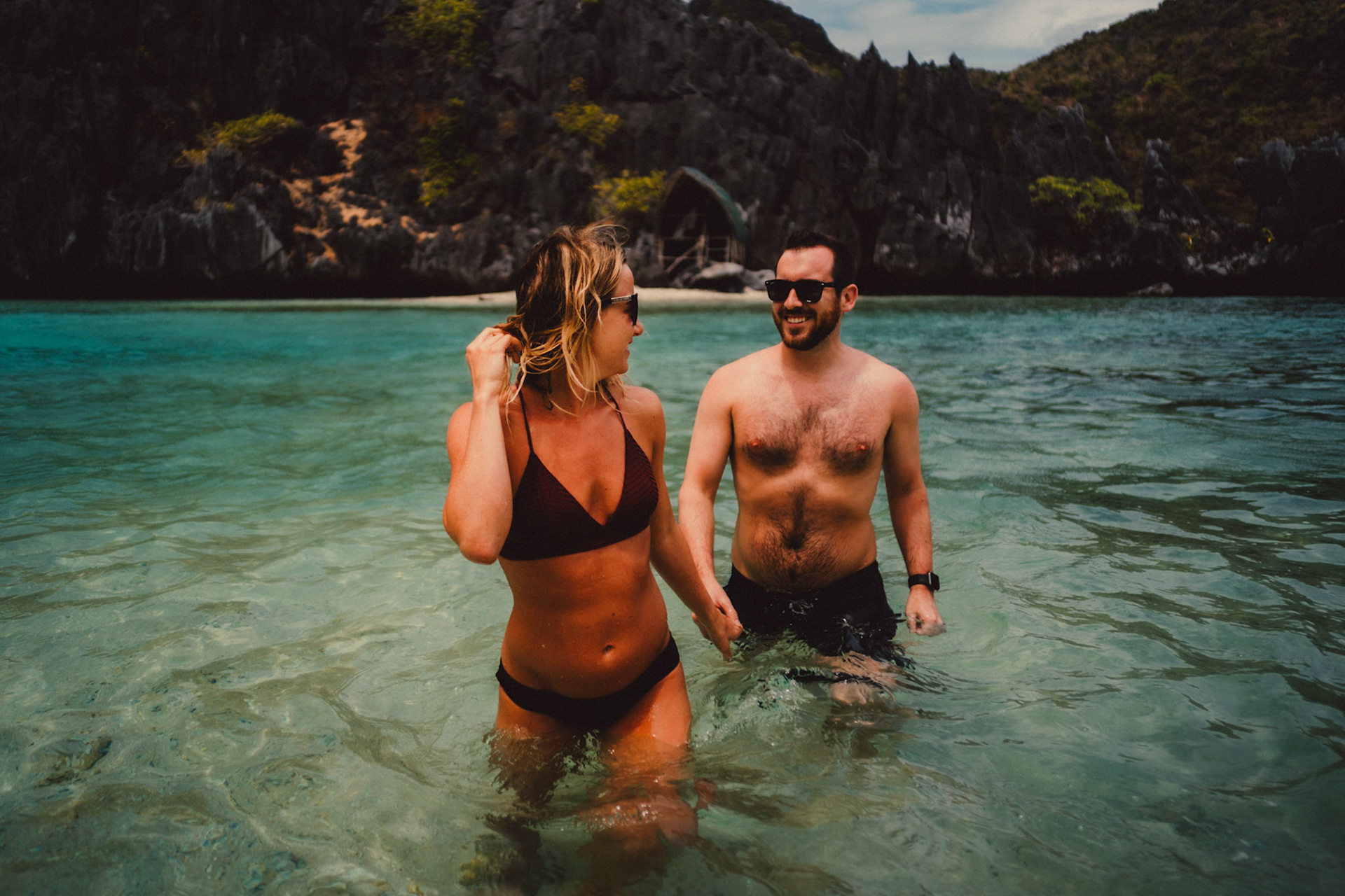 Travel and adventure couple portraits with Skipper Charters, on a cove with a hidden beach with turquoise blue water surrounded by limestone cliffs, Star Beach, Tapiutan Island, El Nido, Palawan, Philippines,Southeast Asia, March 2019, Sony A7III.