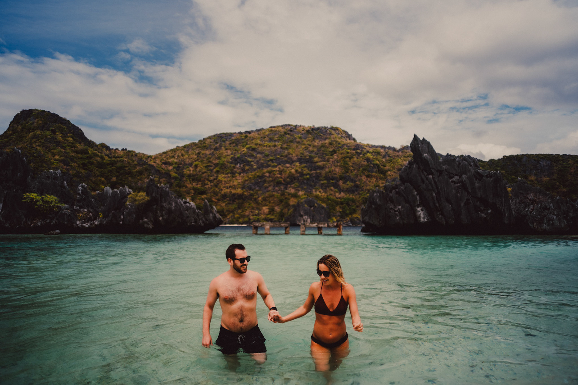 Travel and adventure couple portraits with Skipper Charters, on a cove with a hidden beach with turquoise blue water surrounded by limestone cliffs, Star Beach, Tapiutan Island, El Nido, Palawan, Philippines,Southeast Asia, March 2019, Sony A7III.