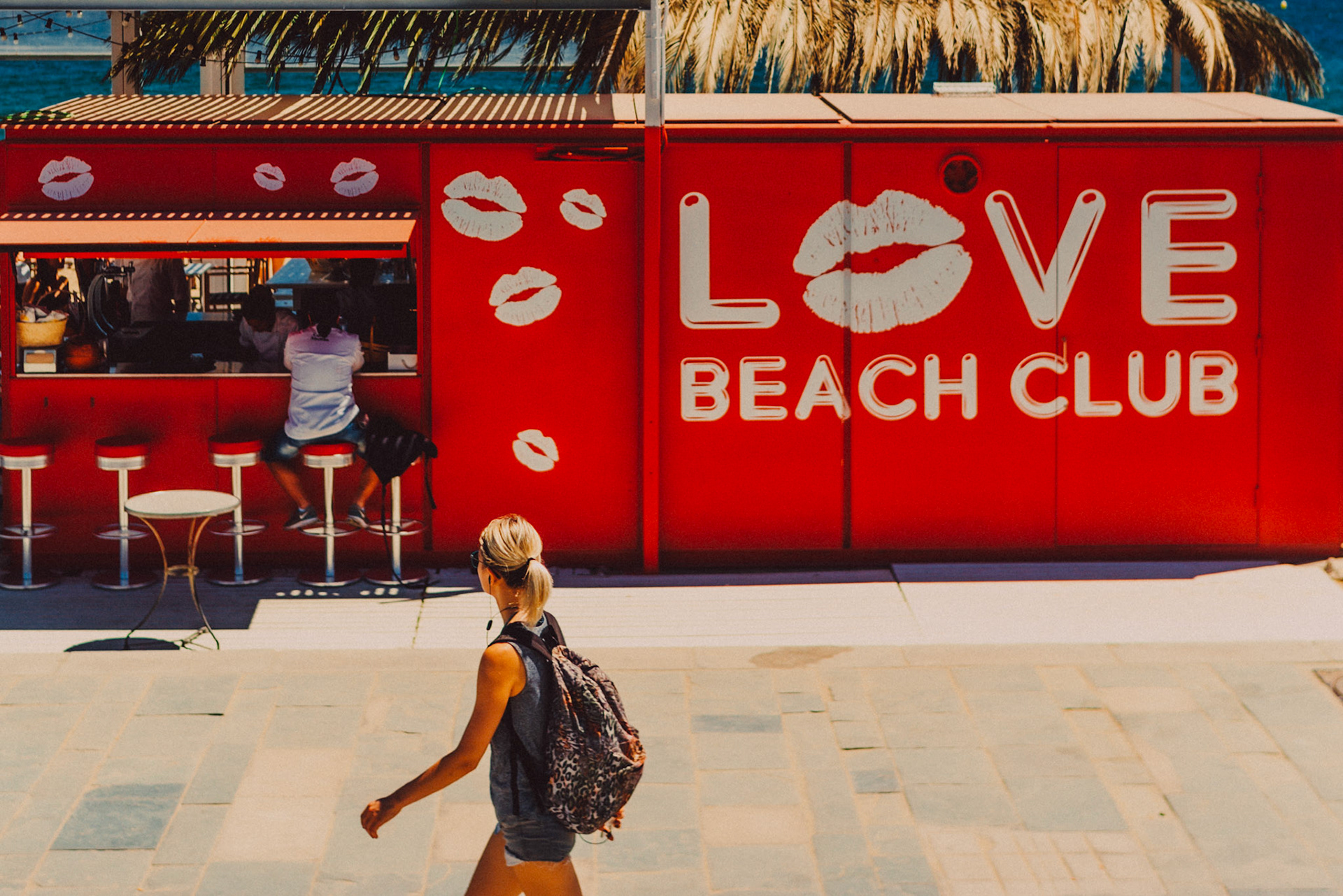 A woman walking along Barceloneta in front of Love Beach Club, Barcelona, Spain, July 2016, Leica M.