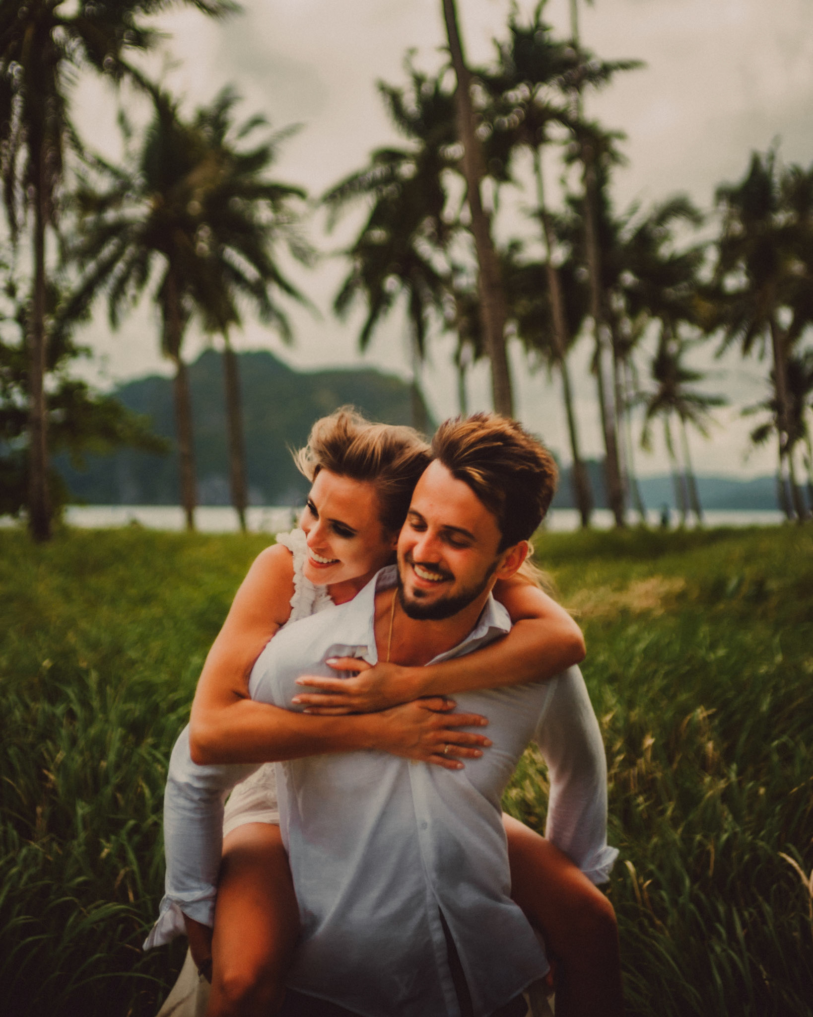Candid couple portraits with knee-high cogon grass and coconut trees in the background, Pinagbuyutan Island, El Nido, Palawan, Philippines, Southeast Asia, December 2019, Sony A7III.