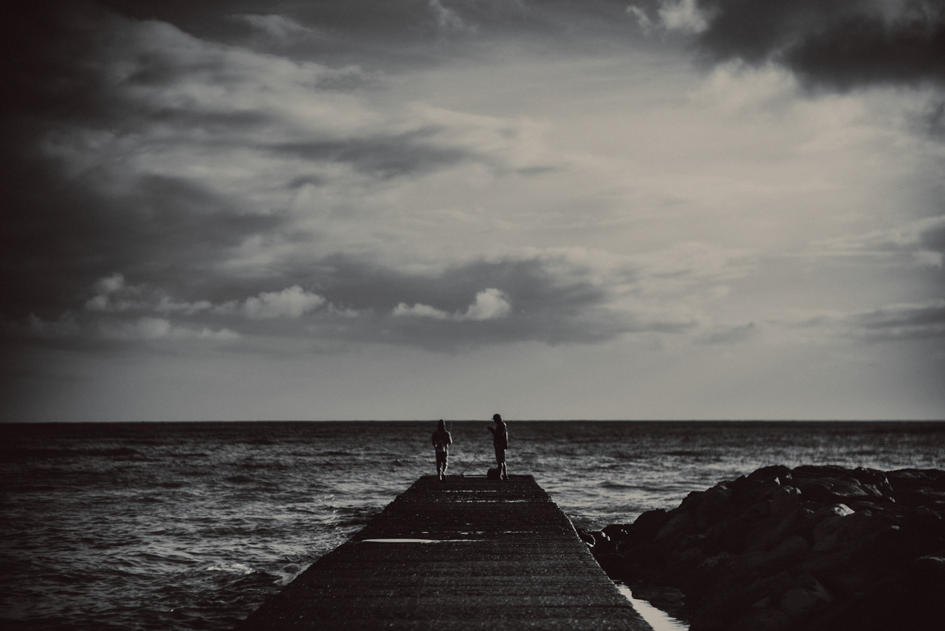 Fishing on a breakwater in Waikiki Beach, in black and white, Honolulu, Hawaii, USA, September 2015, iPhone 6 Plus.