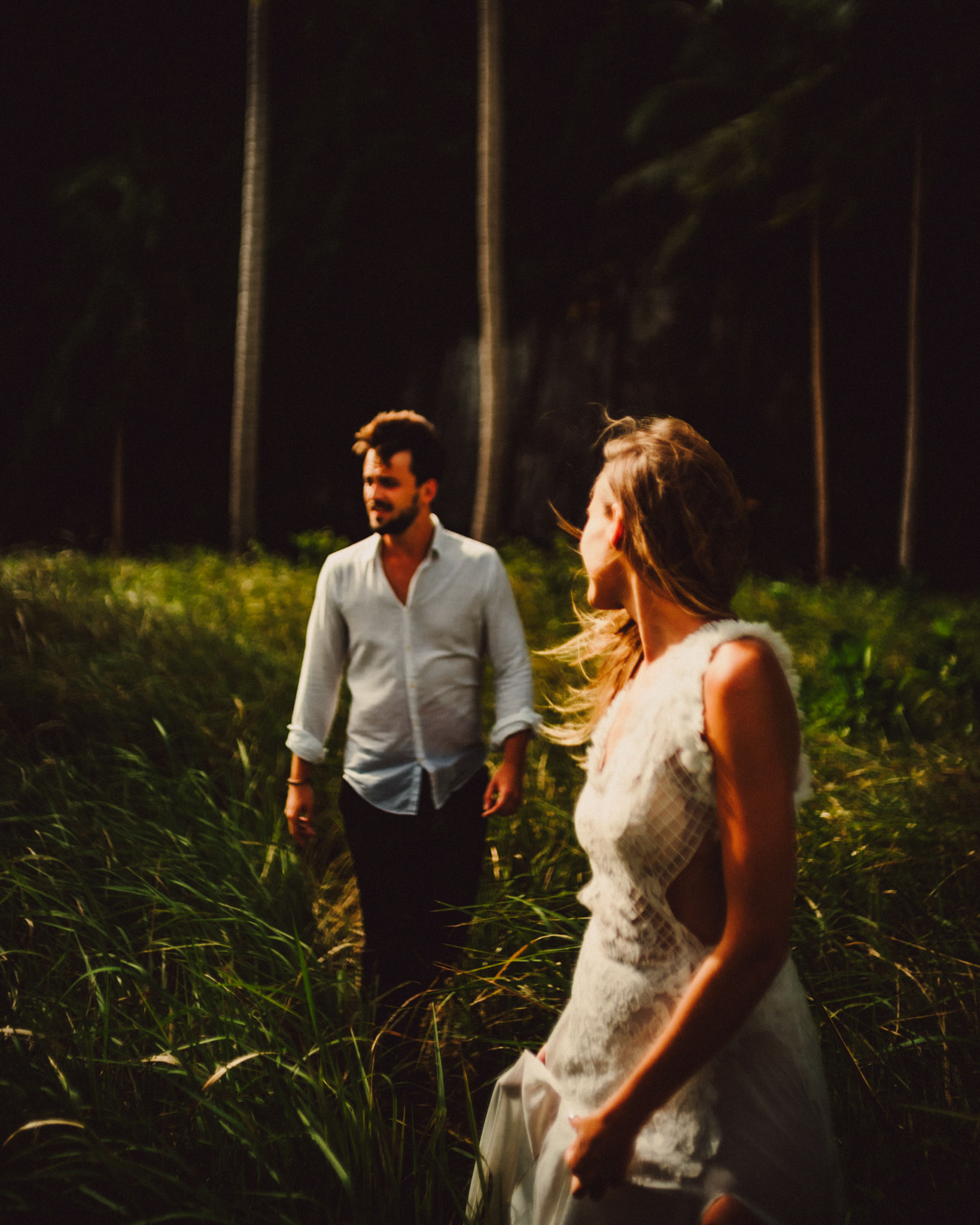 Moody couple portraits with a tropical vibe against a shadowy limestone cliff, palm trees and knee-high cogon grass, Pinagbuyutan Island, El Nido, Palawan, Philippines, Southeast Asia, December 2019, Sony A7III.