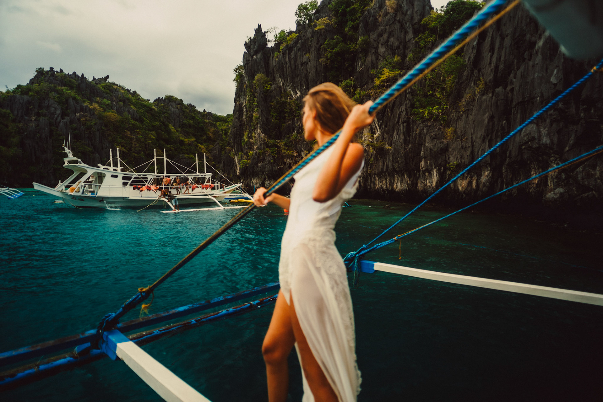 A woman wearing a white dress, standing on an outrigger boat in Miniloc Island, just outside the Small Lagoon, El Nido, Palawan, Philippines, Southeast Asia, December 2019, Sony A7III.