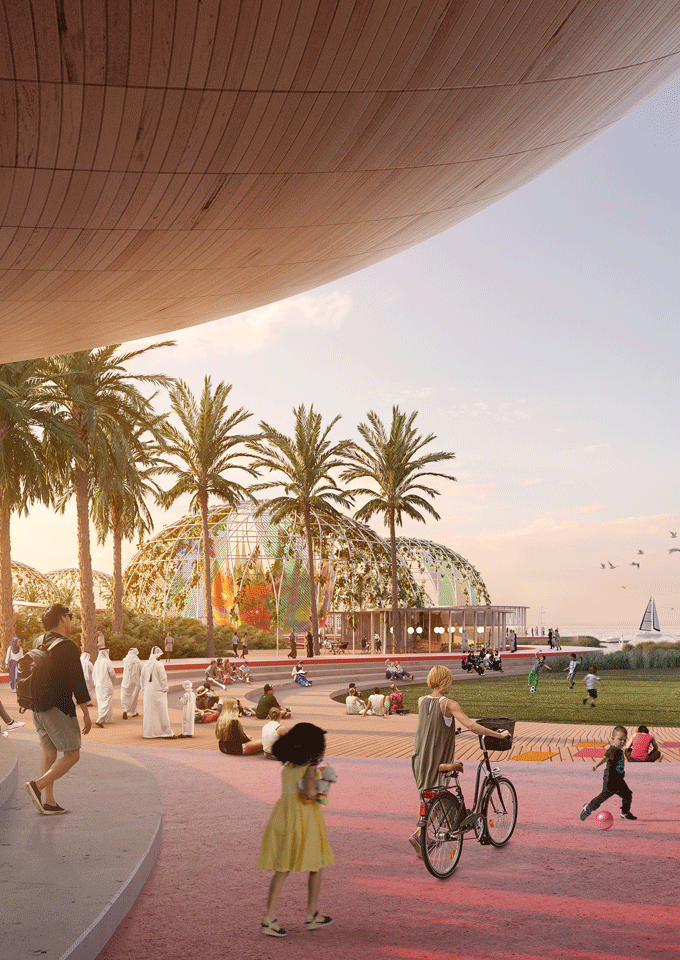 Community driven public space designed with curves and round shapes. Showing a red pathway and wooden boardwalks as steps and open lawn.