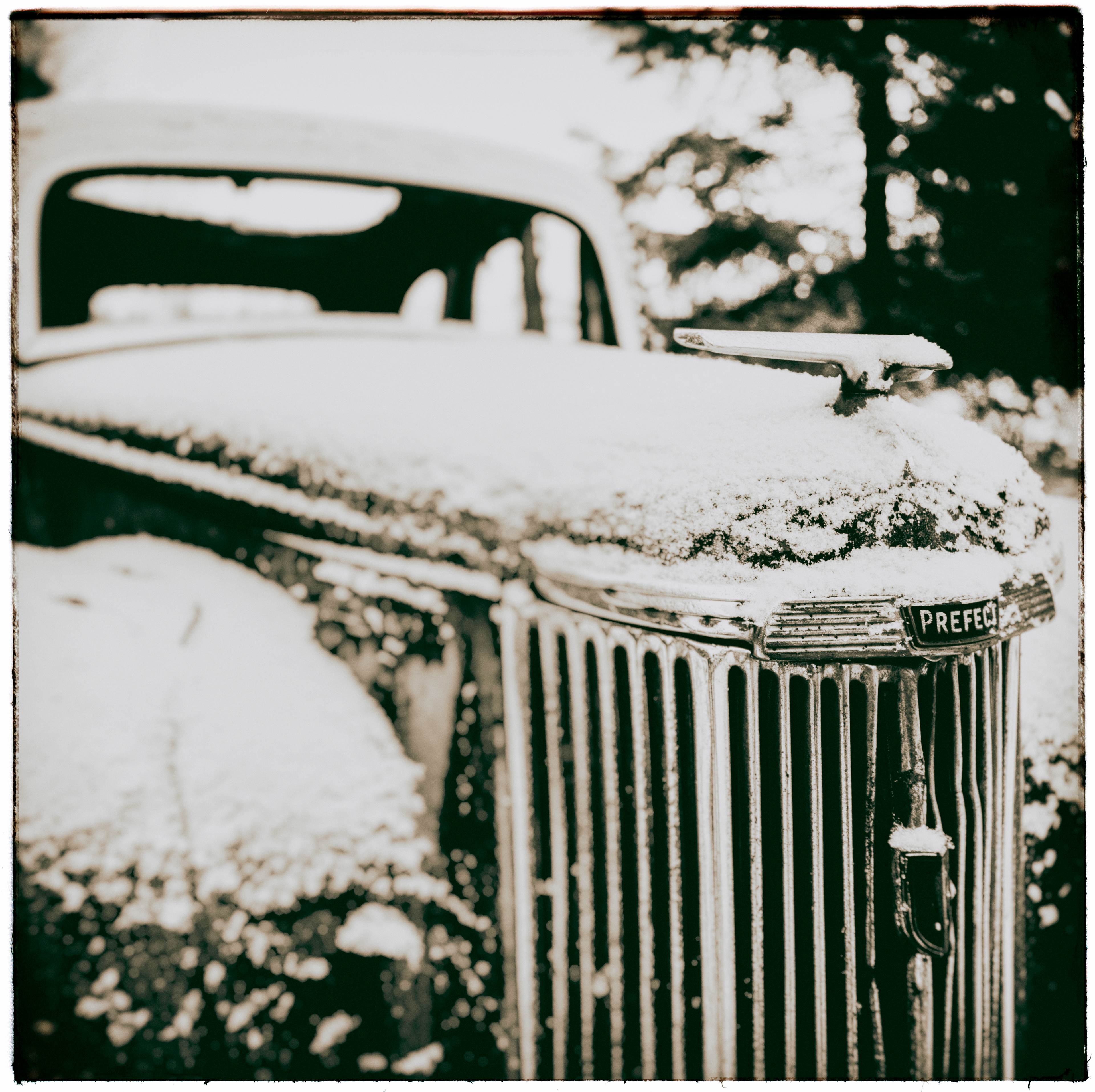 Snow covered front of old decaying vintage Ford Prefect