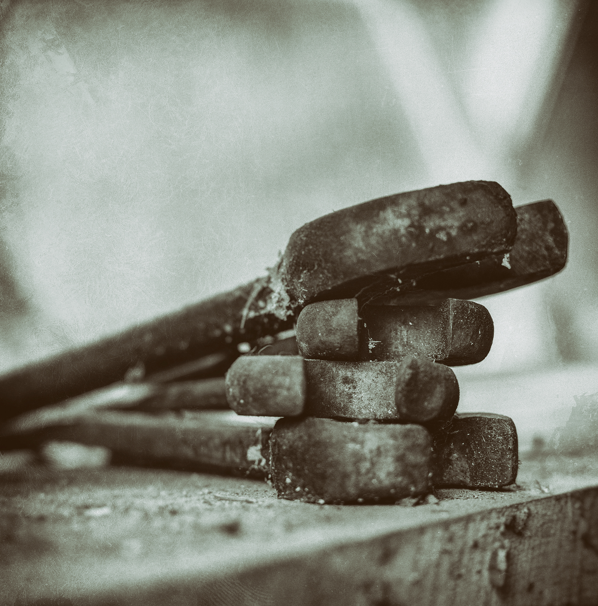 4 wrenches on top of each other on a wooden plank. Photographed with a distressed look and in black and white