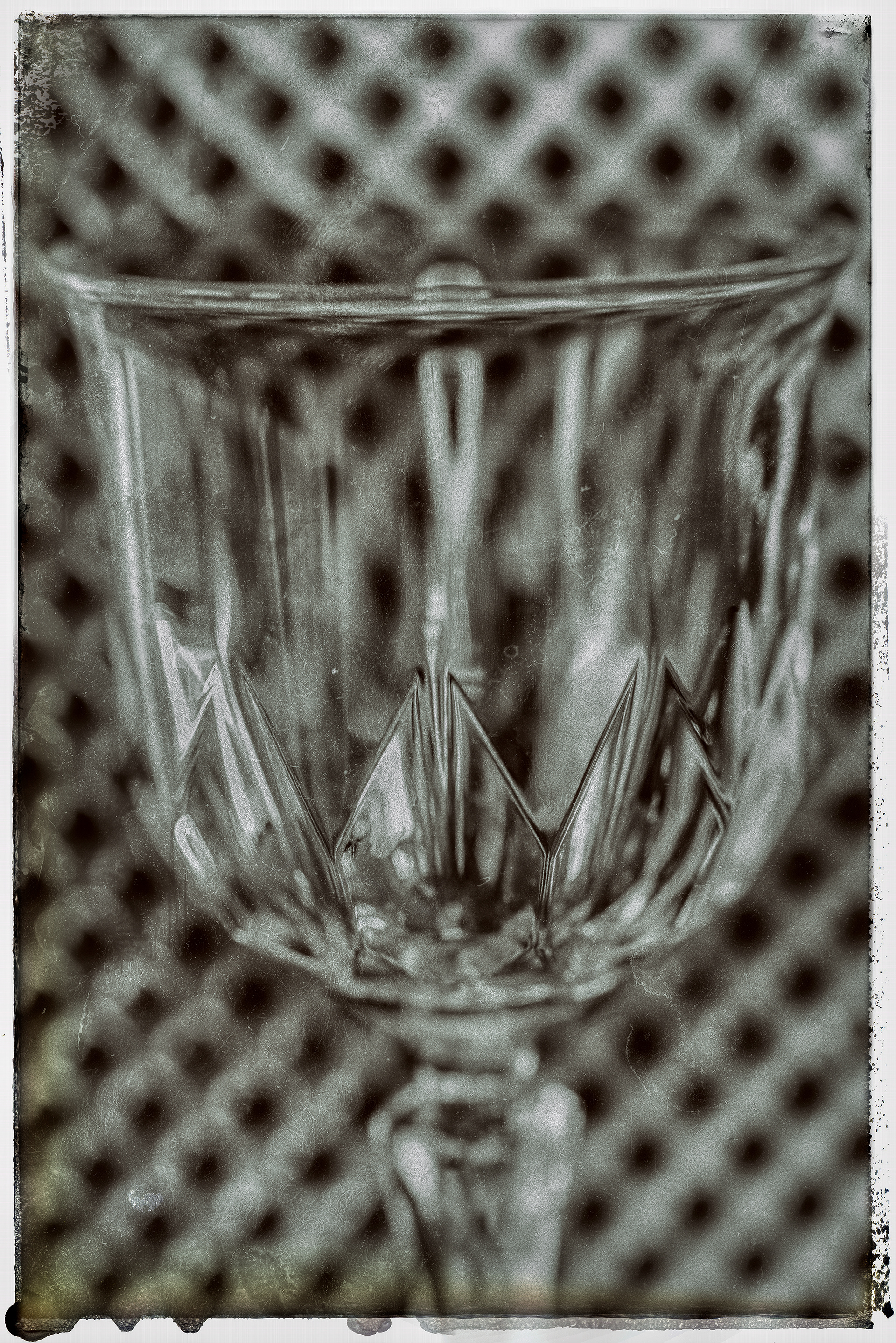 Close up og a sherry glass  with a metal grated background. Short depth of field and in black and white
