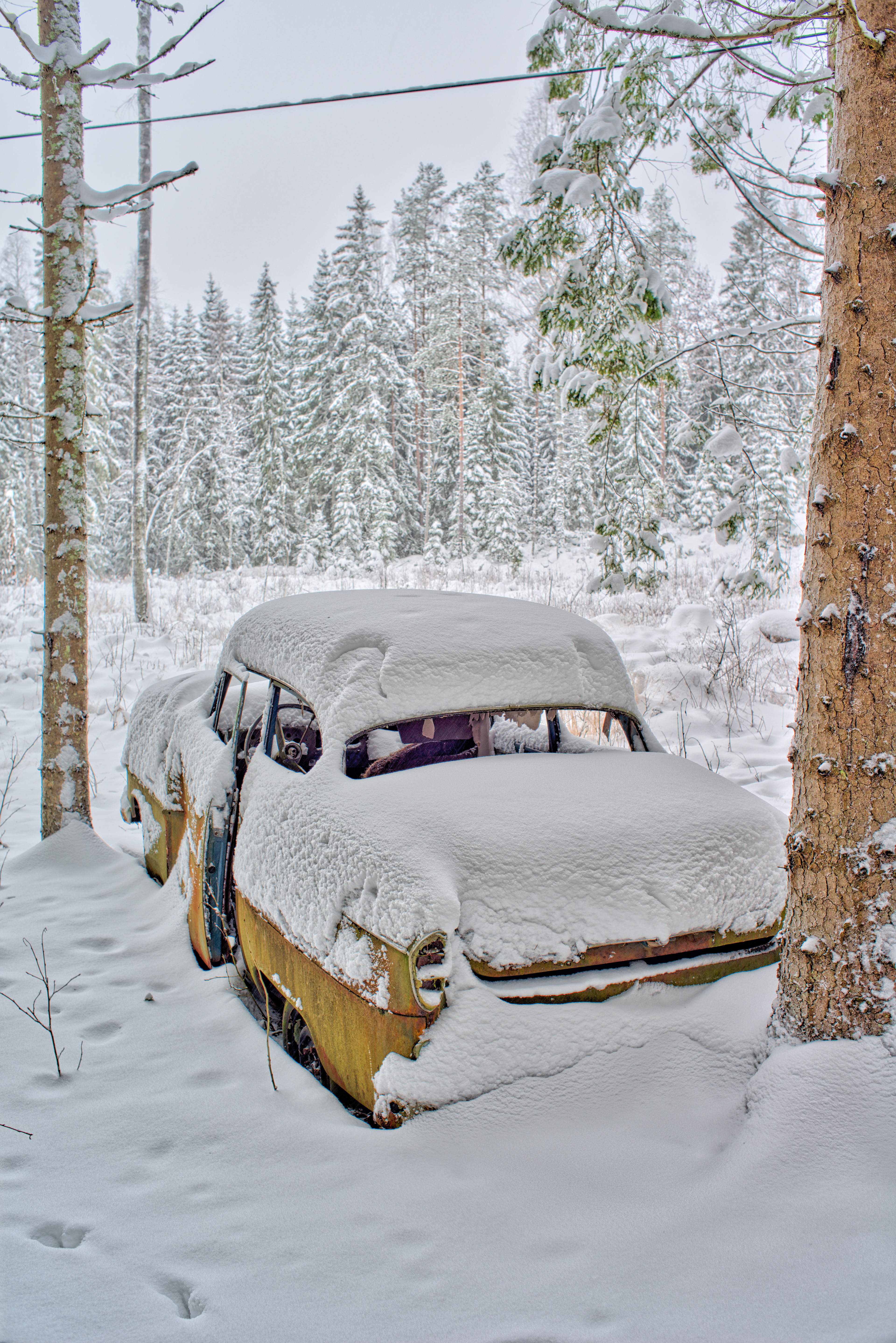 Snow covered old vintage Opel abandoned in the woods in winter