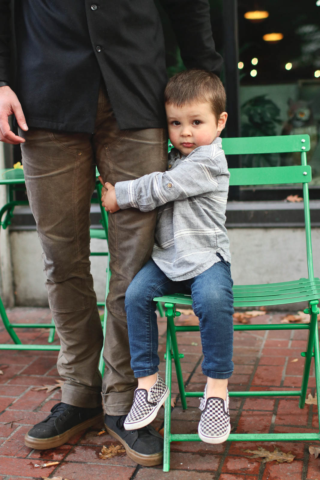 Young boy looking bashful holding onto Dad's leg