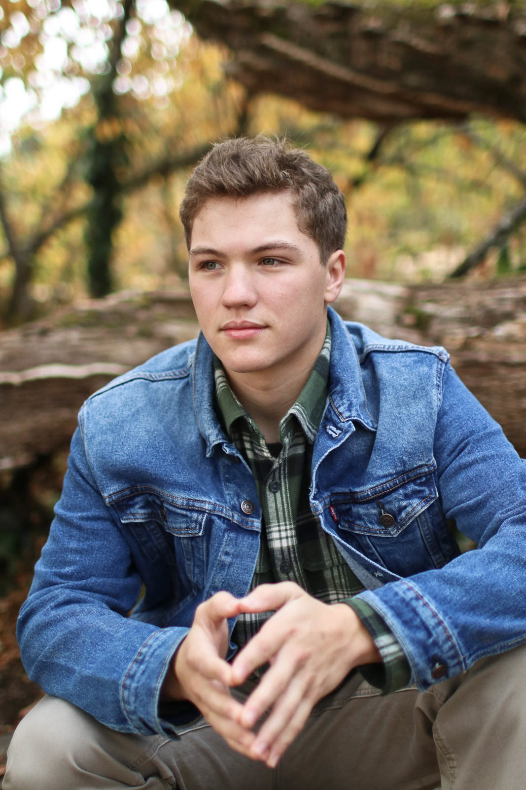 Portrait of teenage boy in denim jacket in a park