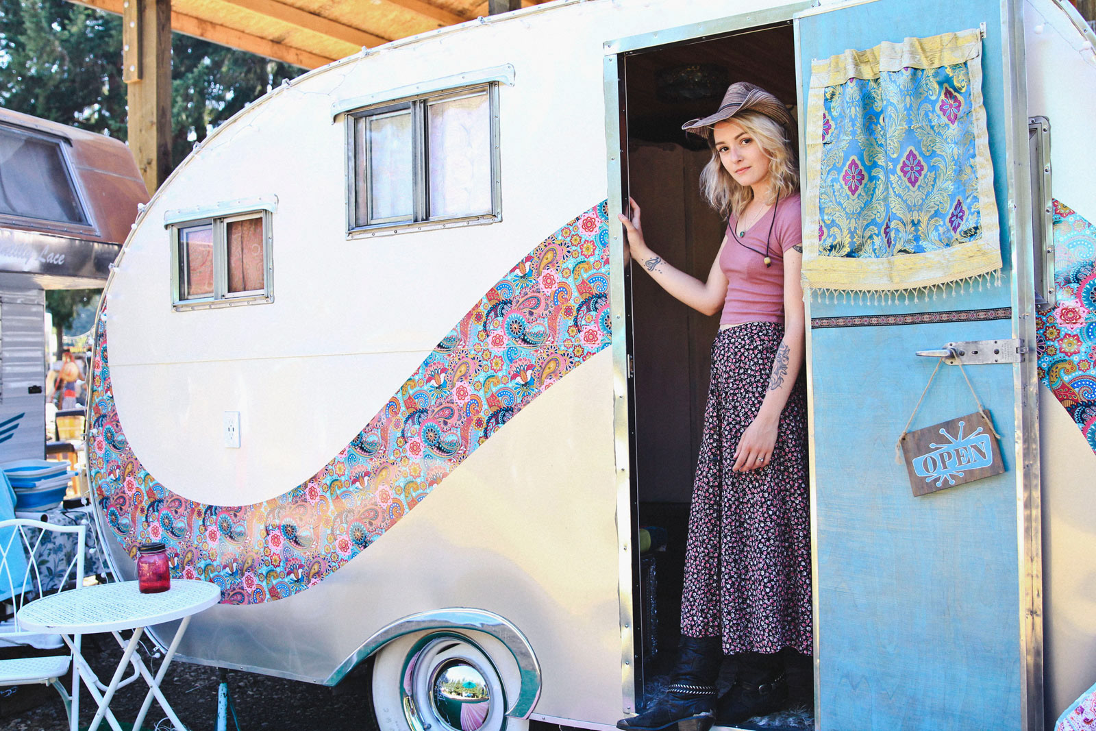 Girl in pink stands in doorway of vintage RV trailer