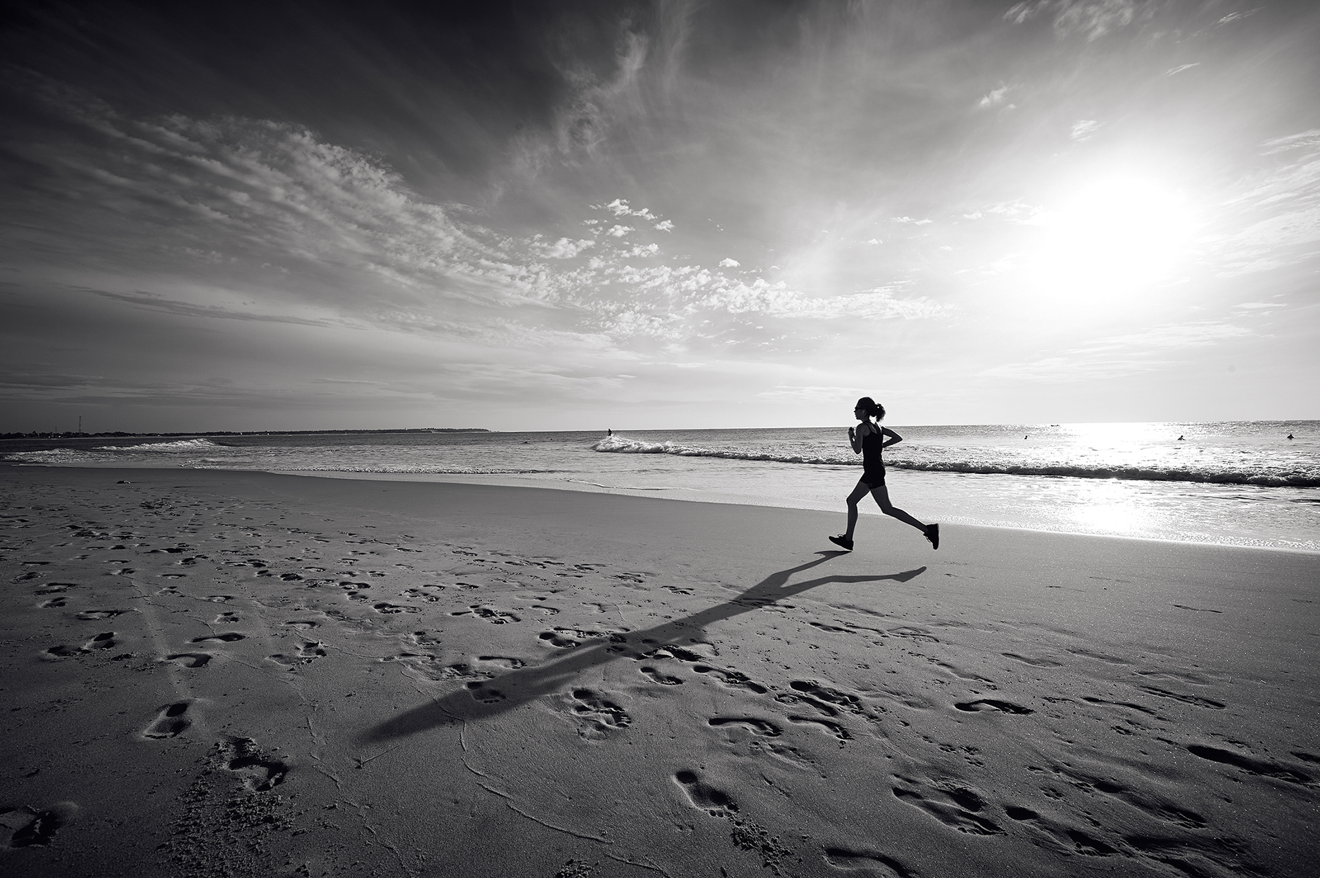 Photograph of runner, silhouetted against whilst running on beach