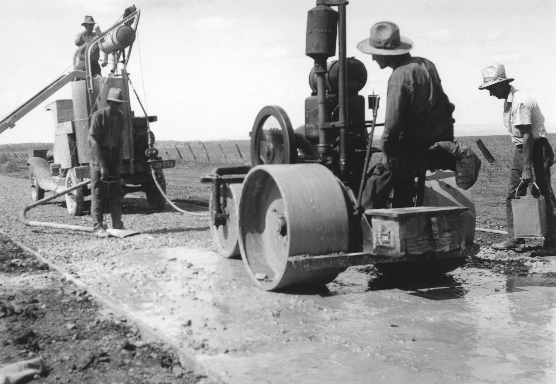 Workers using steel wheeled roller, Construction of an early concrete road near Dalby|Workers using a steel wheeled roller