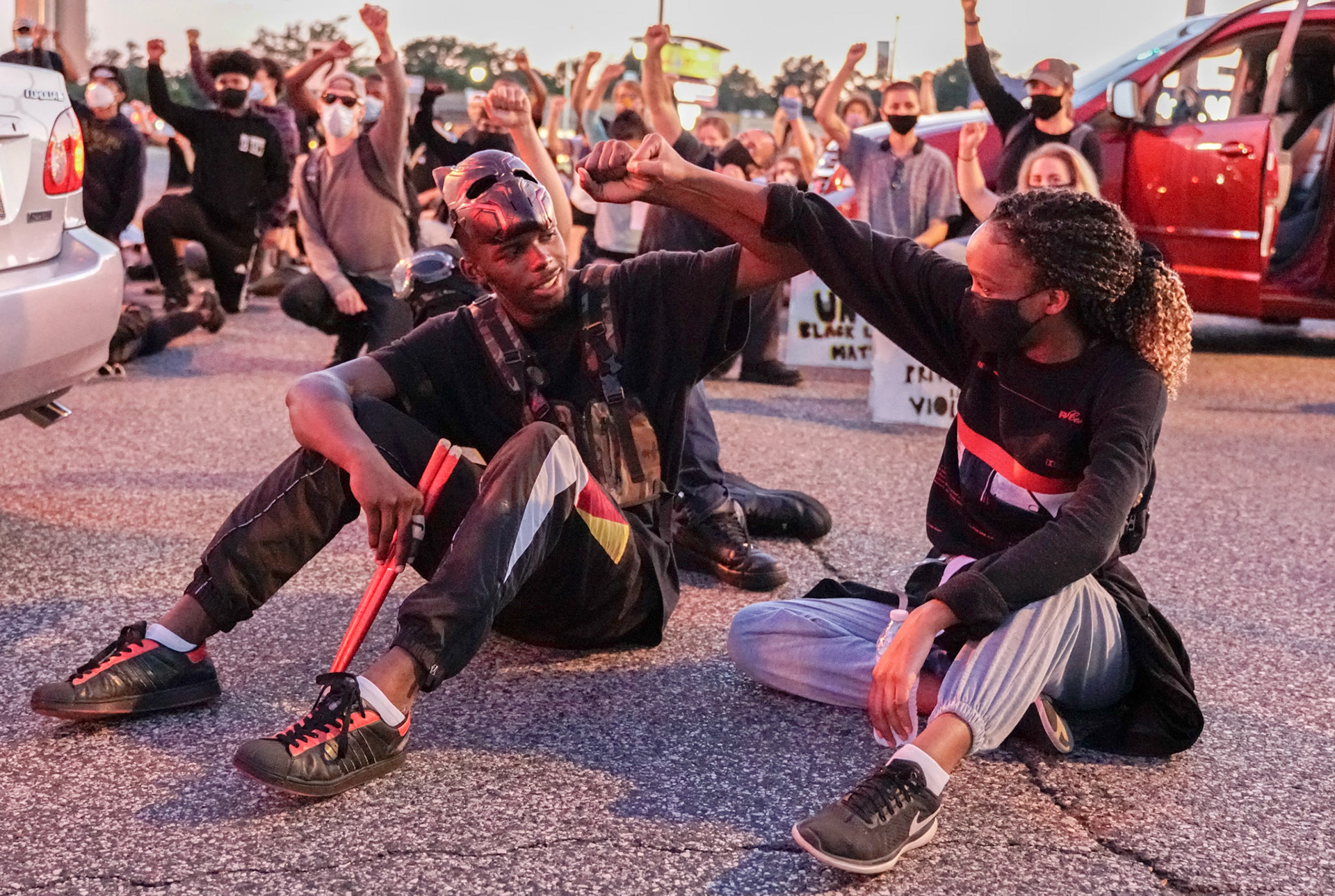 Protestors bump fists in an intersection in Florissant, Mo., during a protest on Wednesday, June 10, 2020. Activists gathered to call for the removal of Florissant detective Joshua Smith after a video was captured of him striking an unarmed man with his car and arresting the man.