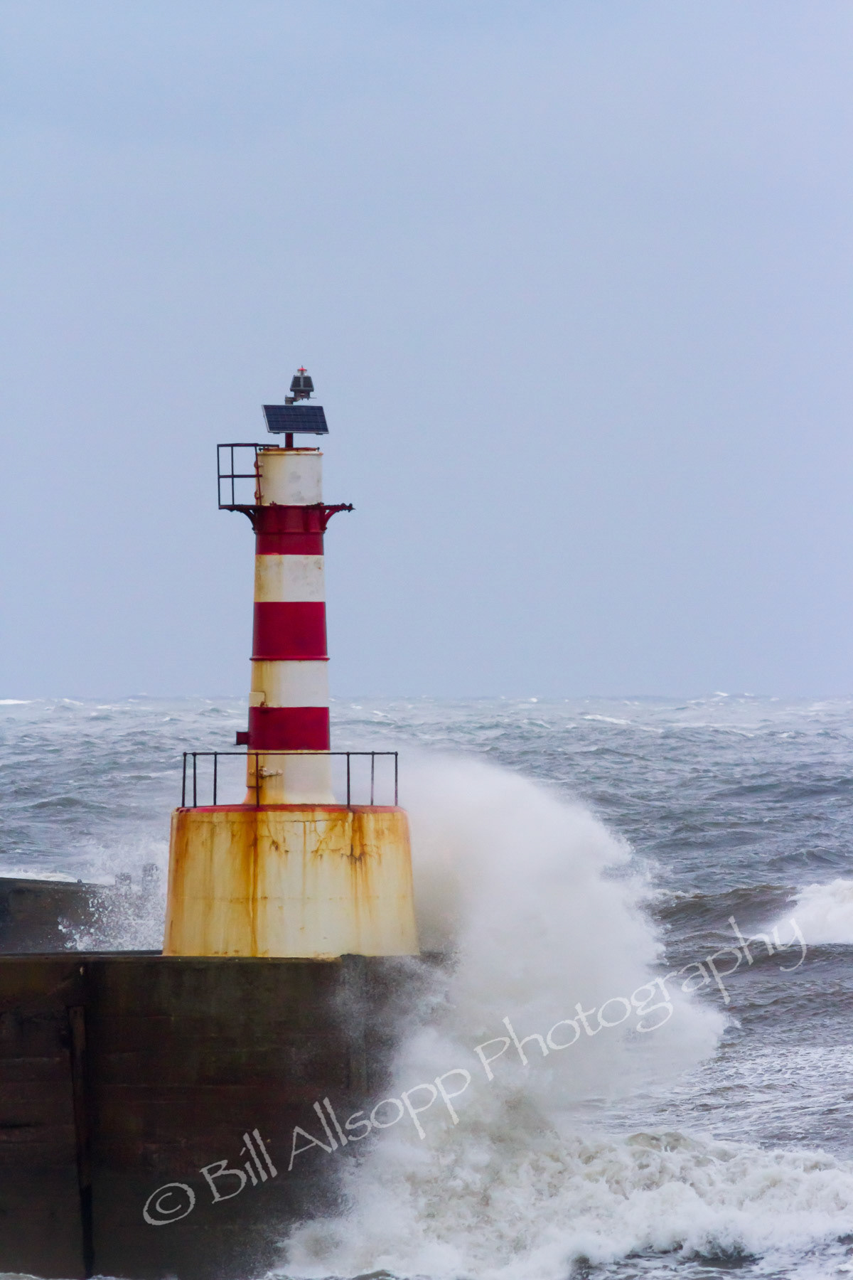 Waves breaking at the harbour light at Amble, Northumberland.