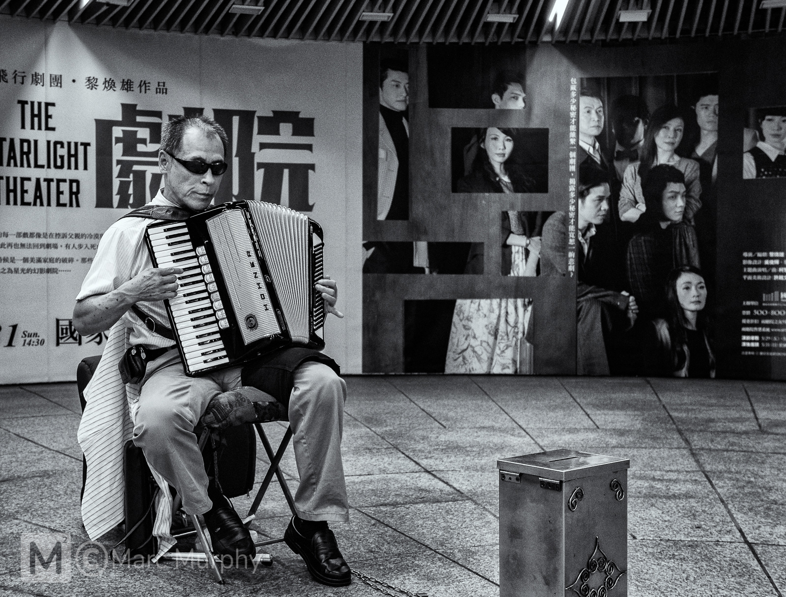 Black and White Taipei Taiwan Subway Station Male Musician Playing the Accordion, Wearing Sunglasses and Sitting in a Chair