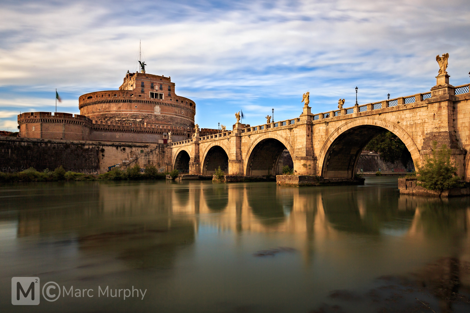 St. Angelo Bridge and Castel Sant'Angelo at Sunset with the River Tiber, Moving Clouds and Blue Sky in Rome Italy