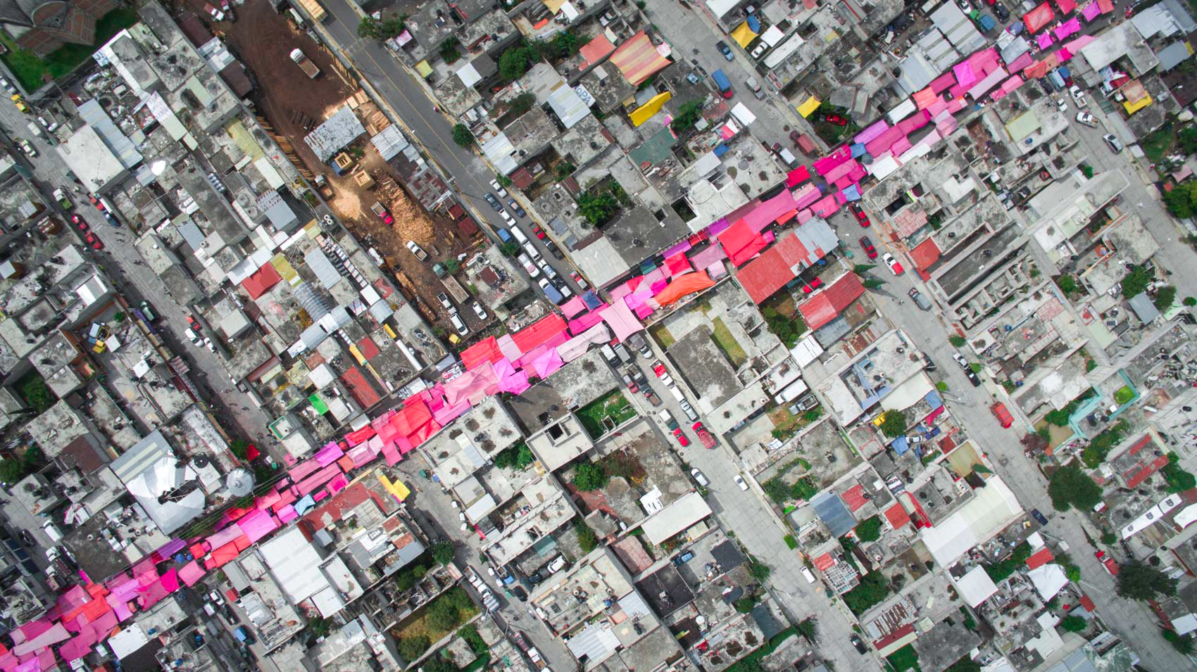 a red stripe on the roofs of a market day in mexico city from the air