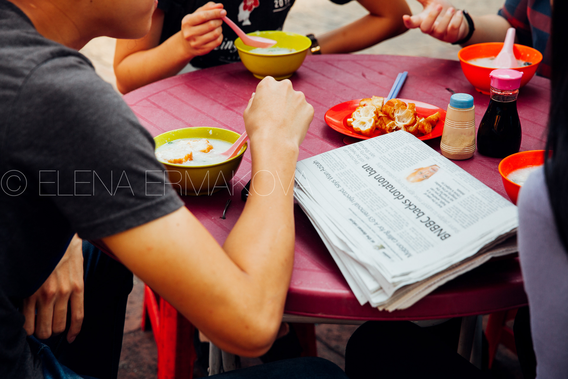 Group of young people having a breakfast with congee and Youtiao in Chinatown, Kuala Lumpur, Malaysia