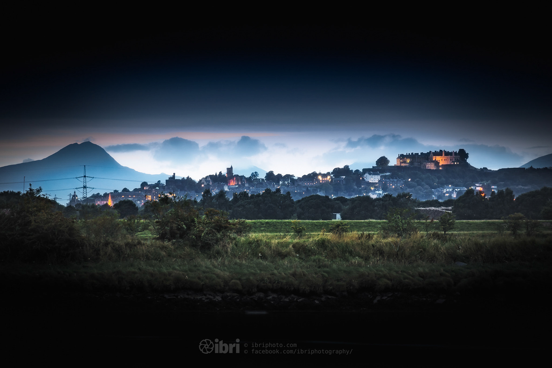 The City of Stirling lights up at dusk, with Ben Lomond silhouetted over to the west.