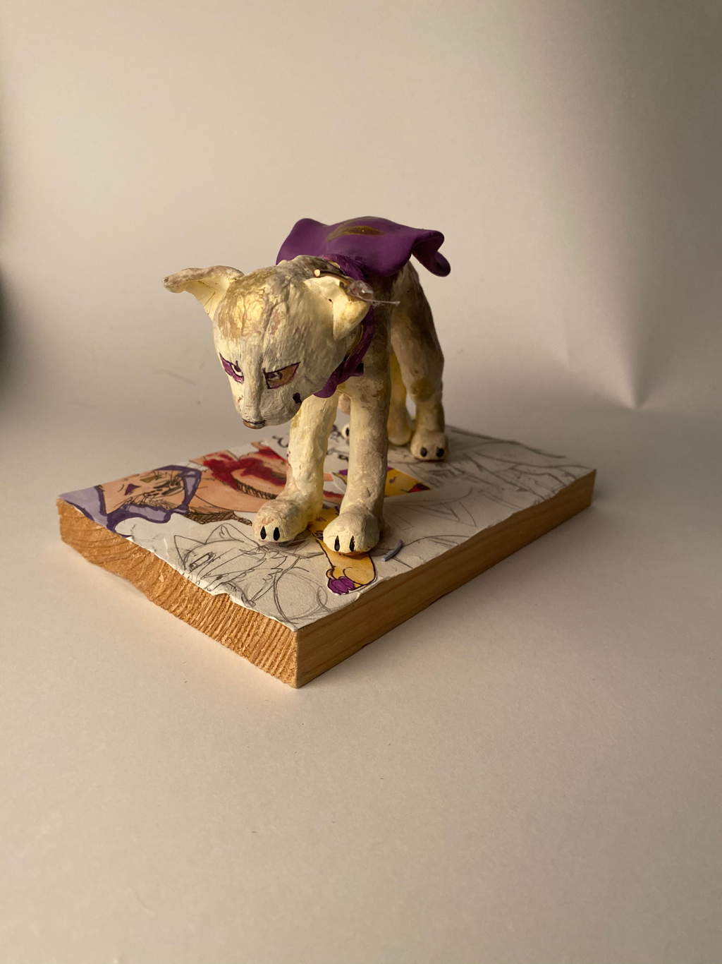 "The Story of Z" | 5" x 8" | Polymer clay mounted on wood collage | My intent with this piece was to create a cat like character that has a worn down feel. To sculpt the form, I made an armature with wire and then began adding muscle to the armature. Then, I painted it to create color and a worn down feel. I glued the cat onto the piece of wood that was collaged with old drawings of him to represent his importance to me and how he’s developed over the years.