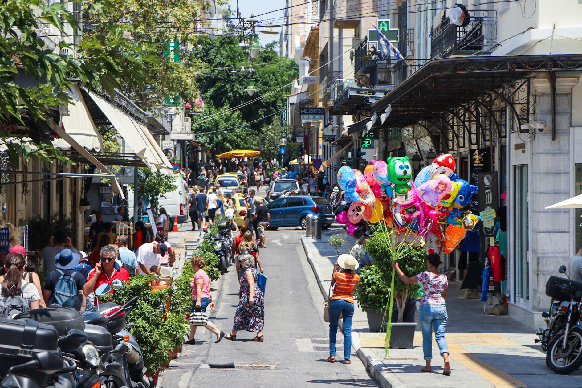 A local of athens rides motercycle back home as two tourists walk towards the center of the city