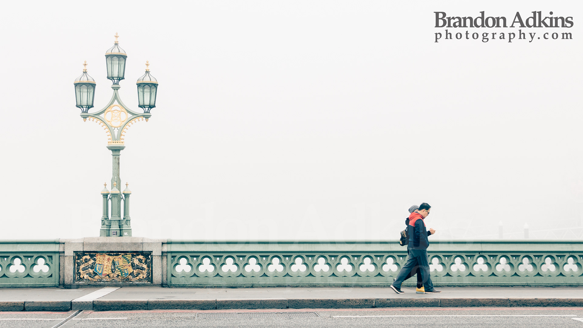 Fine art photograph of two people walking over Westminster Bridge in fog with gold and green ornate street lamp post in London, England, United Kingdom