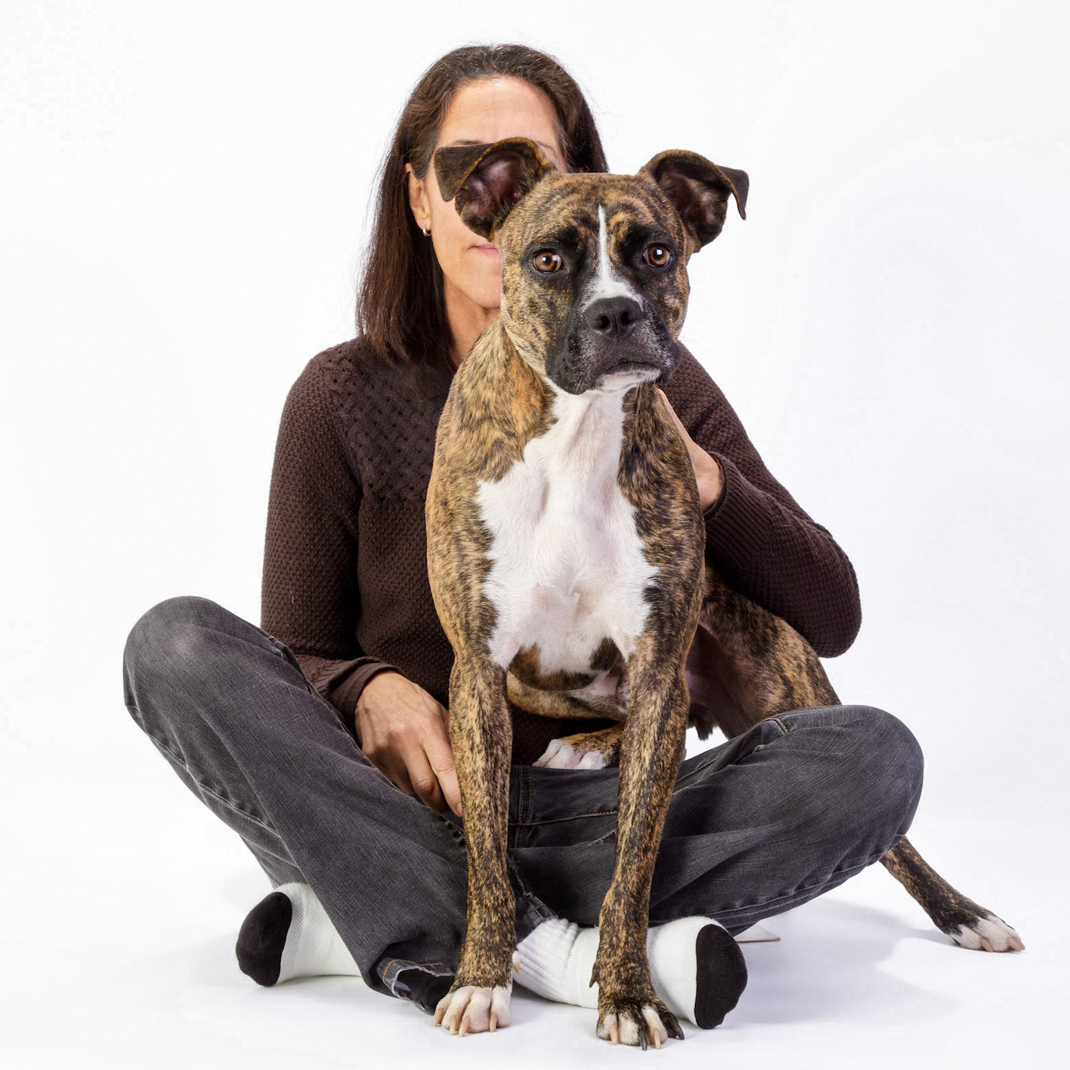 Studio portrait of photographer Cheryl Gottschall of Gott Dog Photography with brindle boxer dog sitting on lap looking at the camera.
