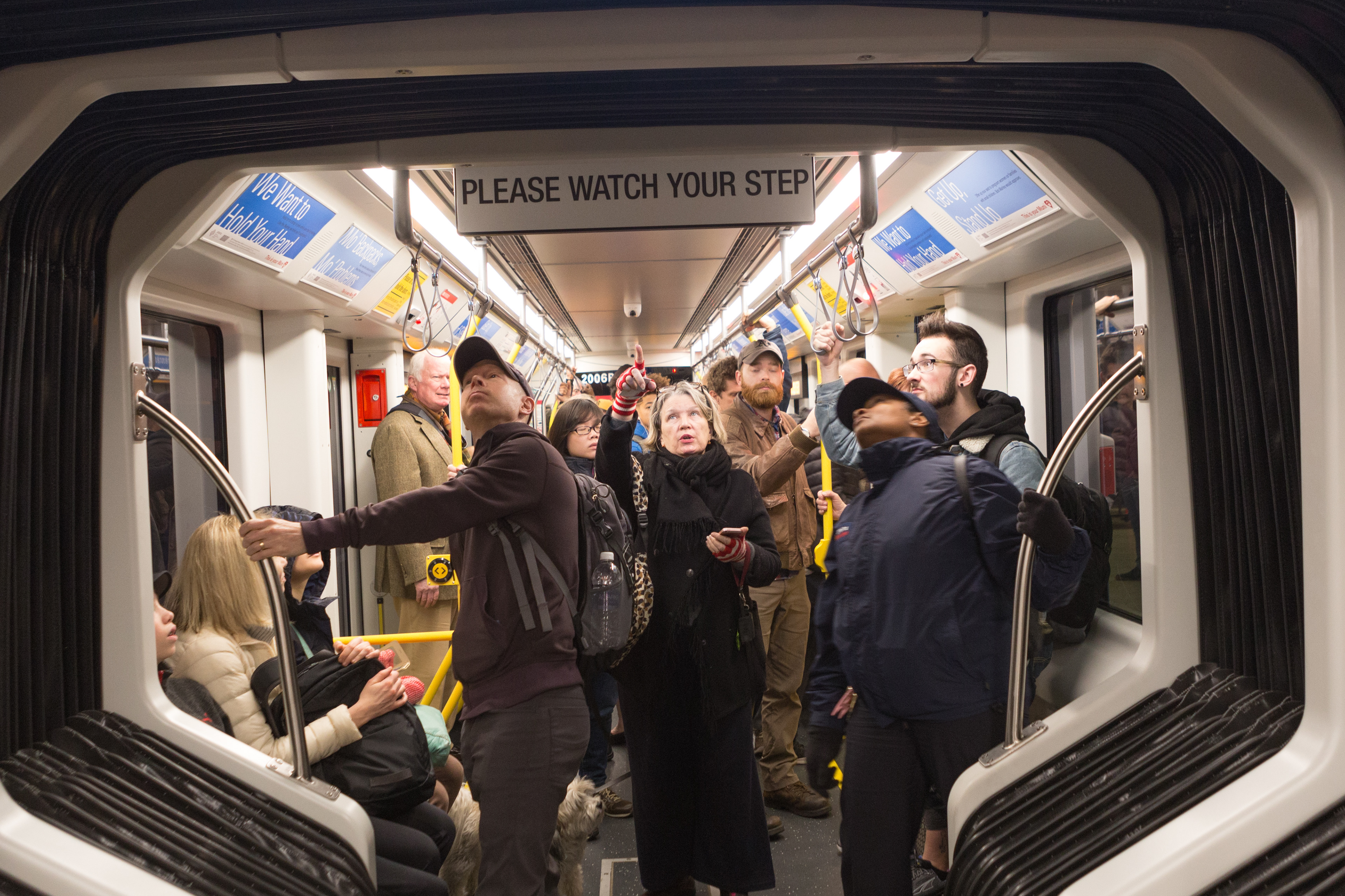 People look at a new sign aboard one of San Francisco's new light rail vehicles in December 2017.