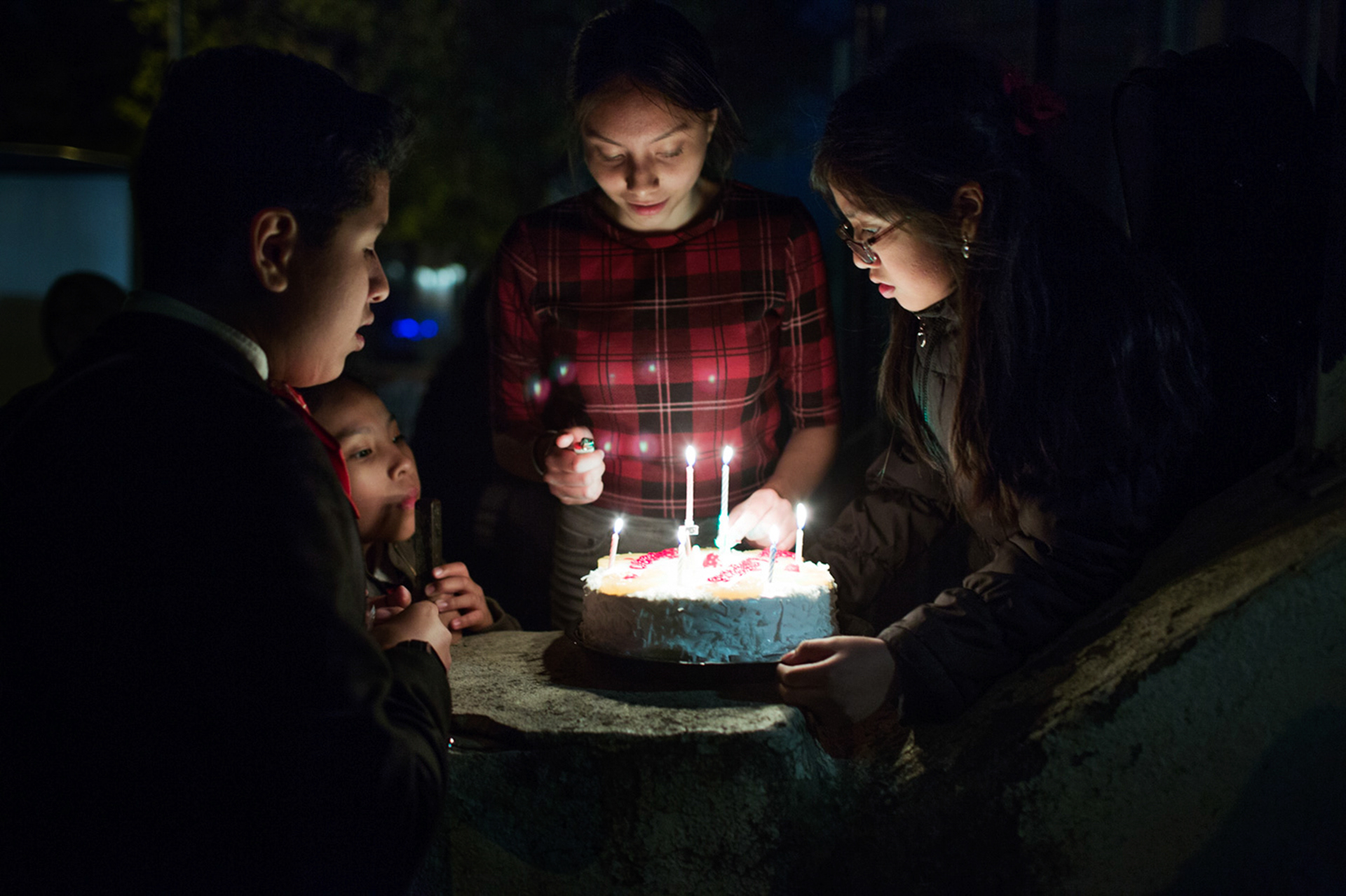 Hillary Garcia lighting the cake for her sister’s 17th birthday. Queens, May 2017.