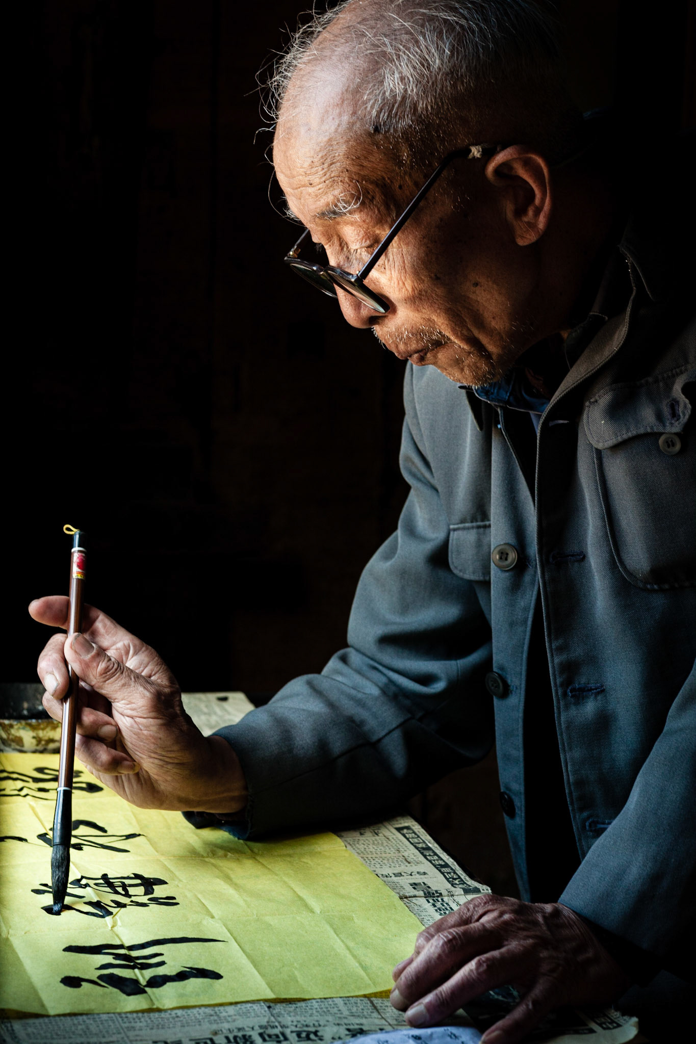 A Chinese Calligrapher making signs using traditional calligraphy in his shop in Shaxi, Yunnan Province, China.