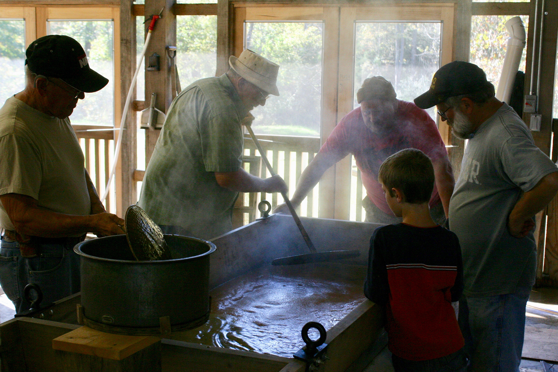 The whole crew present on Thursday, October 19, takes a peek into the “finishing pan,” where the sorghum cooks slowly to its final temperature of 226.9 degrees Fahrenheit with a sugar concentration of 78-82%. The smell inside the mill changes as the sorghum cooks, from an earthy beginning to a distinctly sweet aroma by the end. The tranquil, yet deliberate pace of the cooking process leads one to imagine they have indeed stepped back in time in the recreated mill, built exactly as it would have been found in the 1890s.