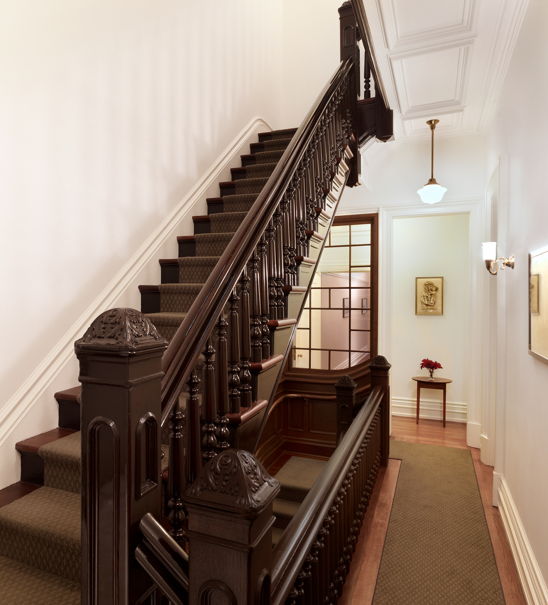 Renovated townhouse stair in dark stained wood.