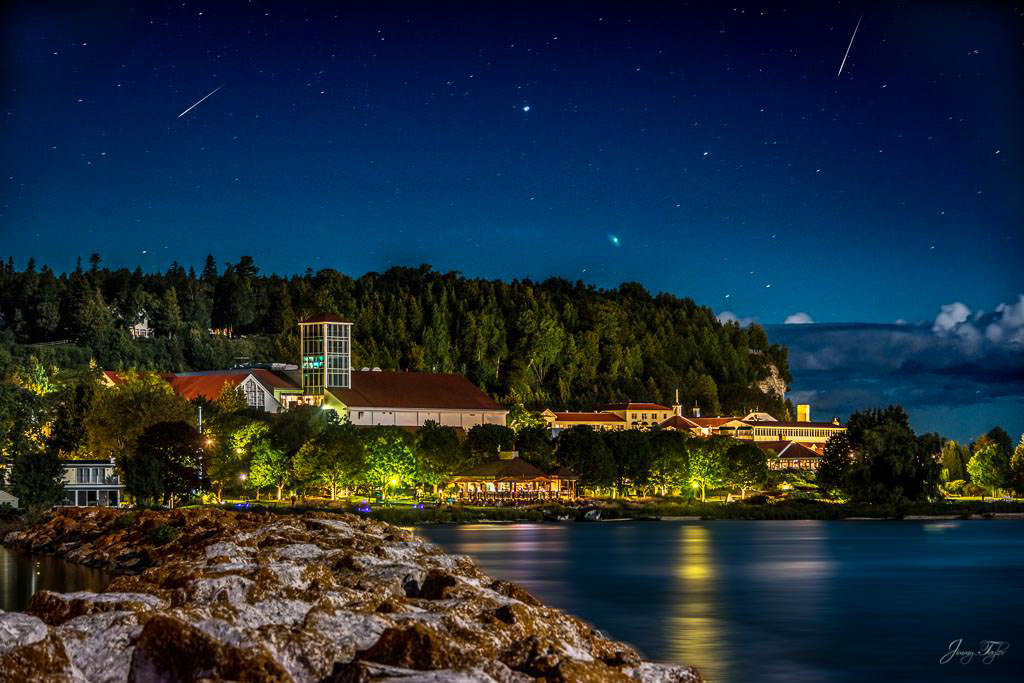 Mackinac Island at night with incredible view and reflection on the water of Mission Point Resort and shooting stars