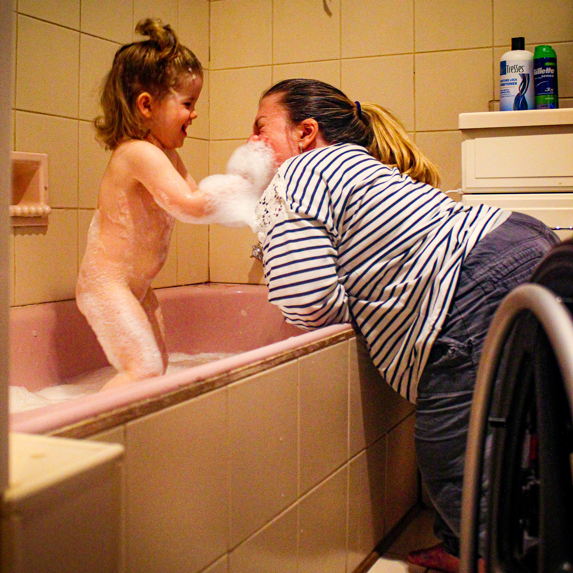 Bath time with a toddler, in a pink bathroom, with Malissa leaning over the bathtub