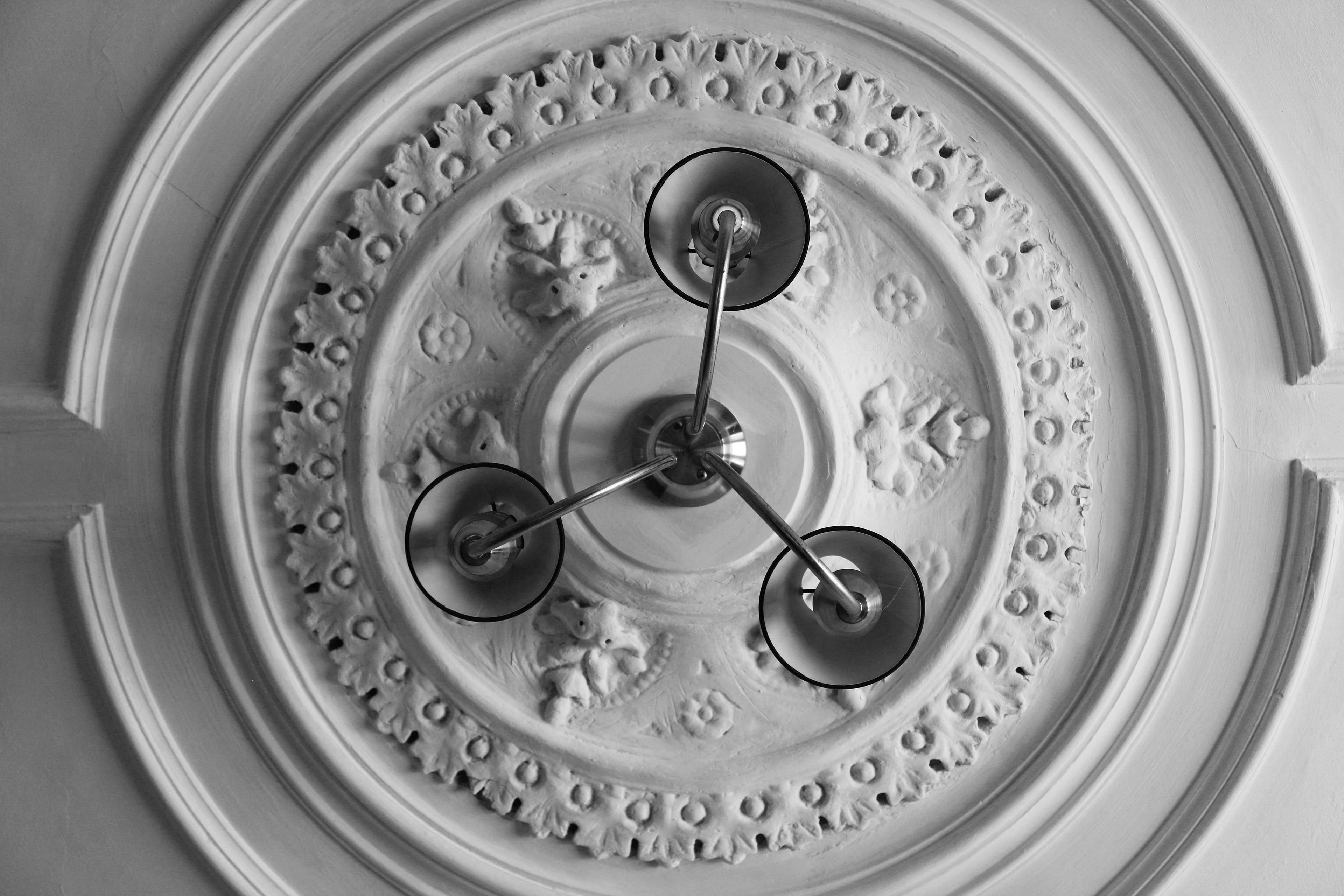 Shot looking up the ceiling, 3 prong lamp and ceiling art work