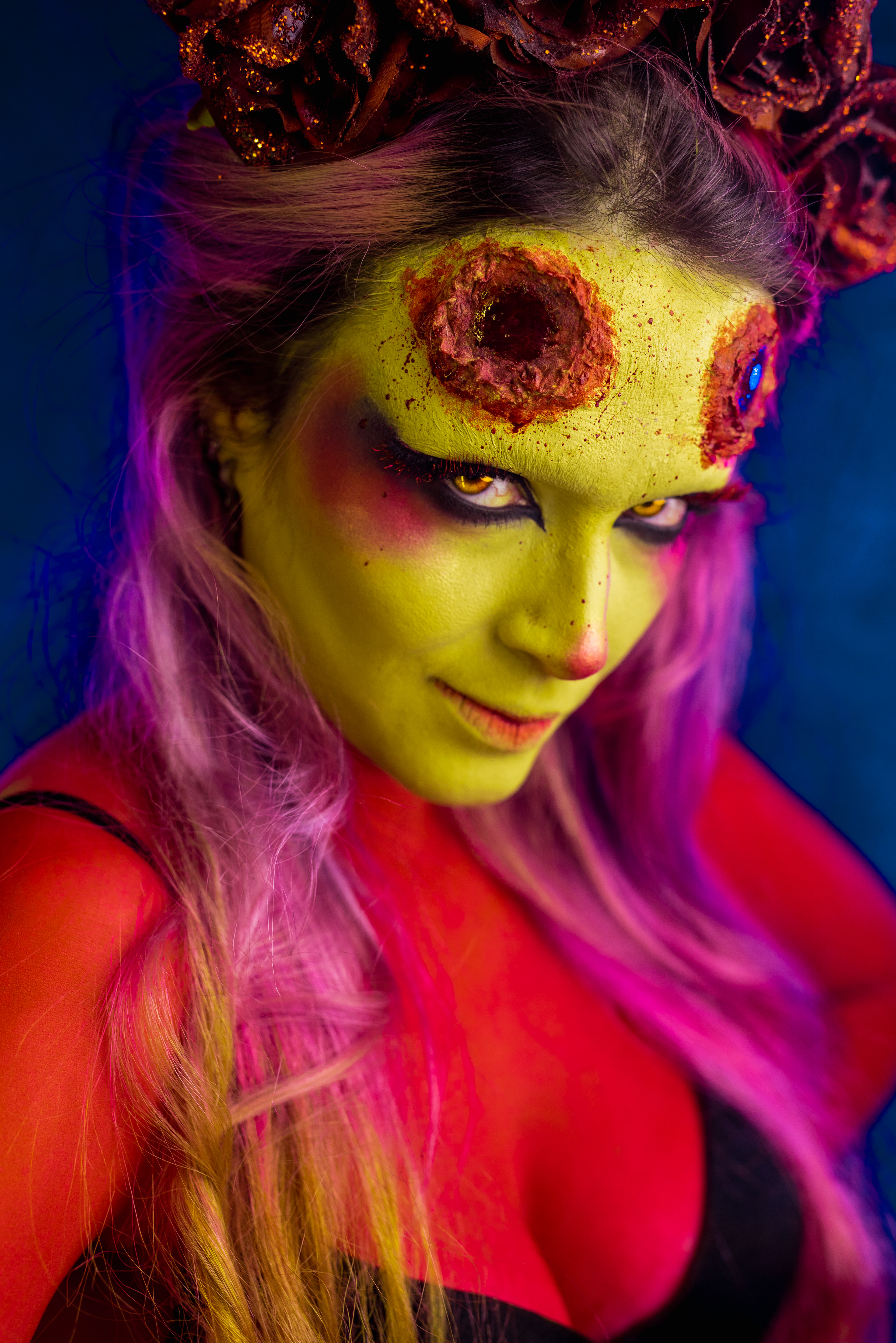 demon woman artistic makeup red skin yellow eyes on black background