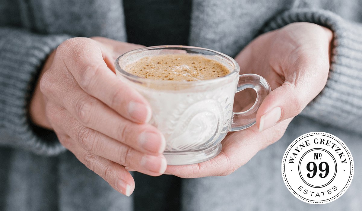 Image of person holding a glass mug containing a hot holiday drink