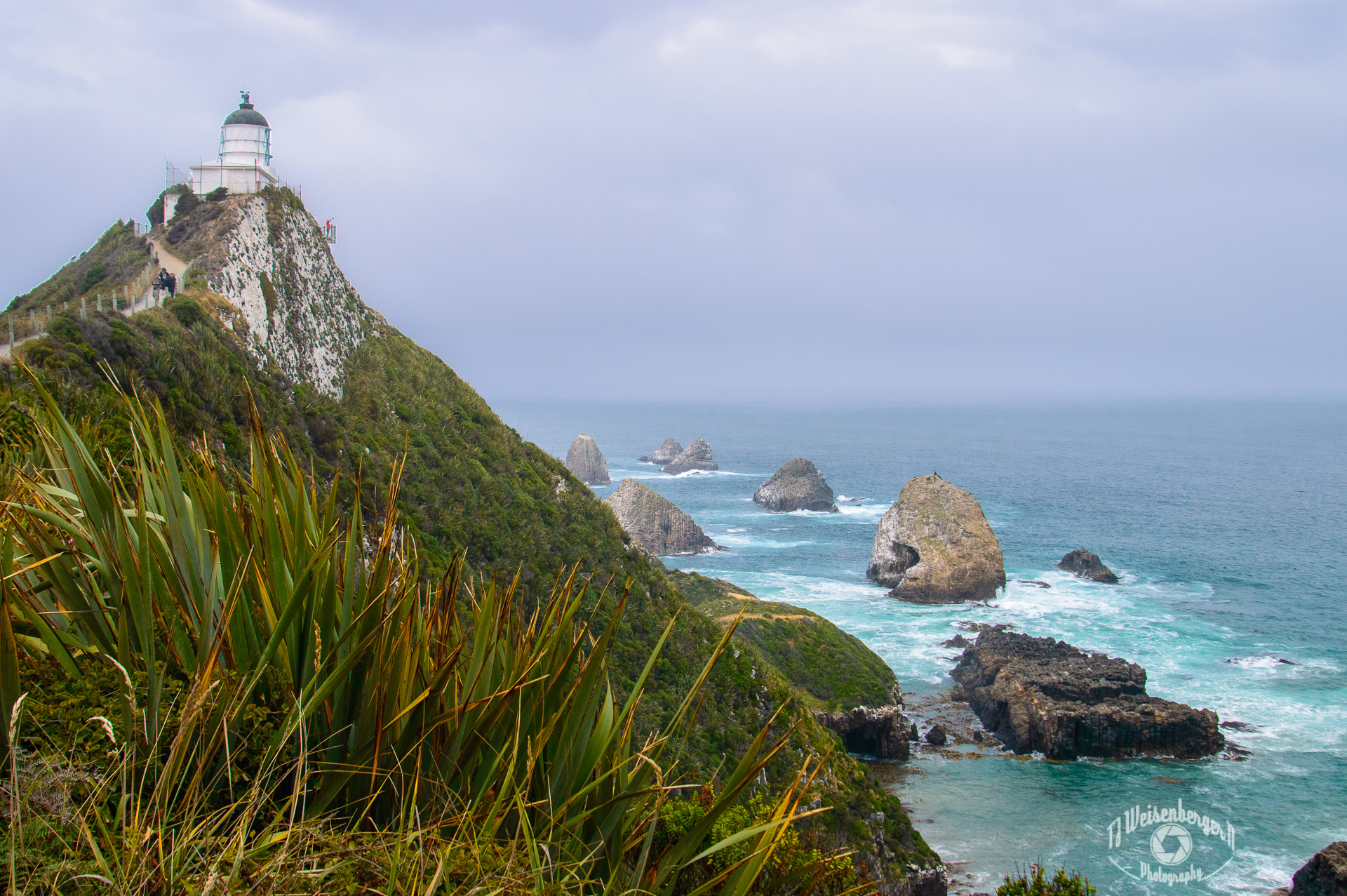 Moody Seascape, Nugget Point Lighthouse - South Island, New Zealand; Cloud - Sky; Cloudy; Coastal; Coastline; Landscape; Landscape - Scenery; Lighthouse; New Zealand; Nugget Point; Ocean; Pacific; Photography; Plants; Rocks; Scenics - Nature; Sea; Sea Stacks; Seascape; South; South Island; Southern Ocean; Summer; Tourism; Travel; Travel Destinations; flora; nature; outdoors; T.J.; TJ; Weiseberger
