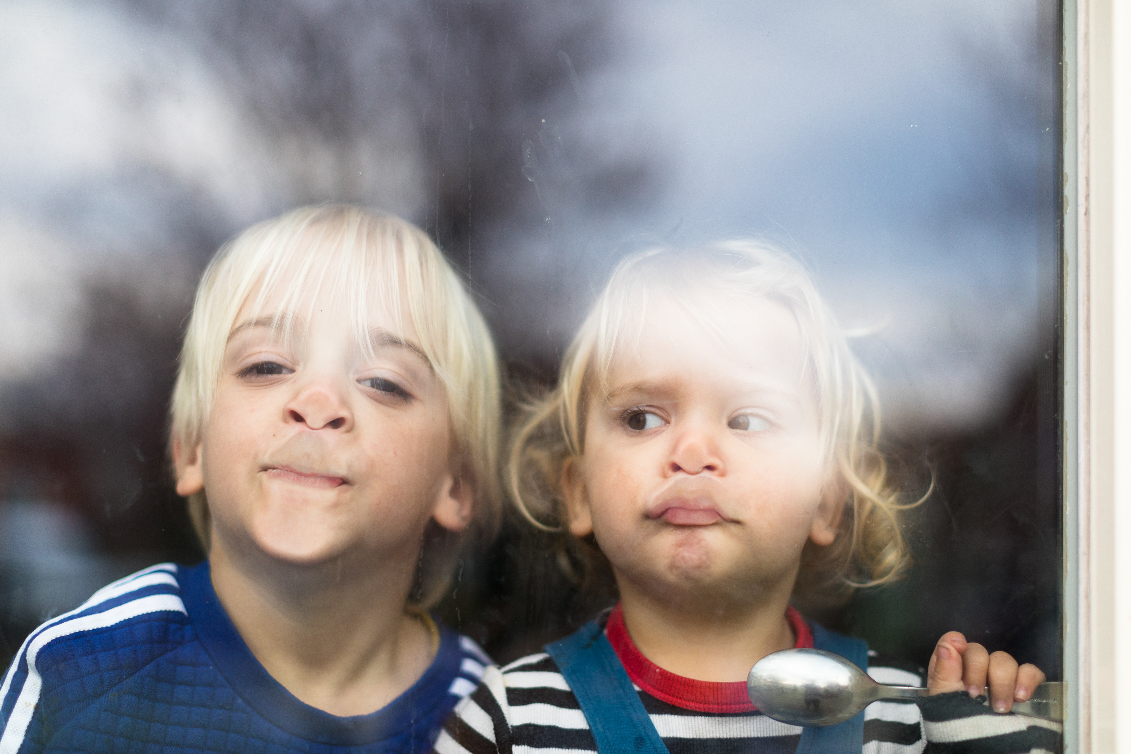 Twee kinderen die graag naar buiten willen ten tijde van Corona in Enschede. De gezichten tegen het raam geplakt. 