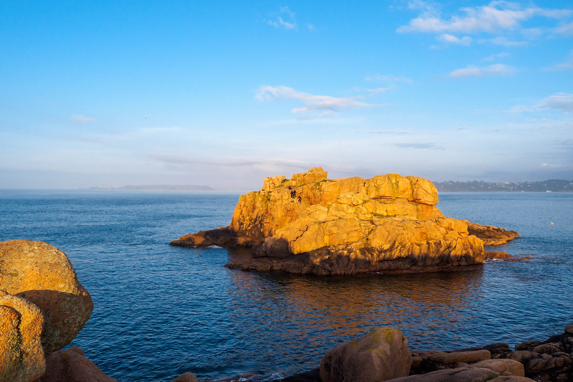 Under a blue sky during a golden sunset, a small group of daredevil divers prepared to jump off this cliff in Ploumanach, Bretagne.