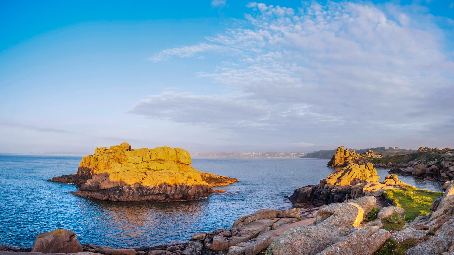 Under a blue sky during a golden sunset, a small group of daredevil divers prepared to jump off this cliff in Ploumanach, Bretagne.