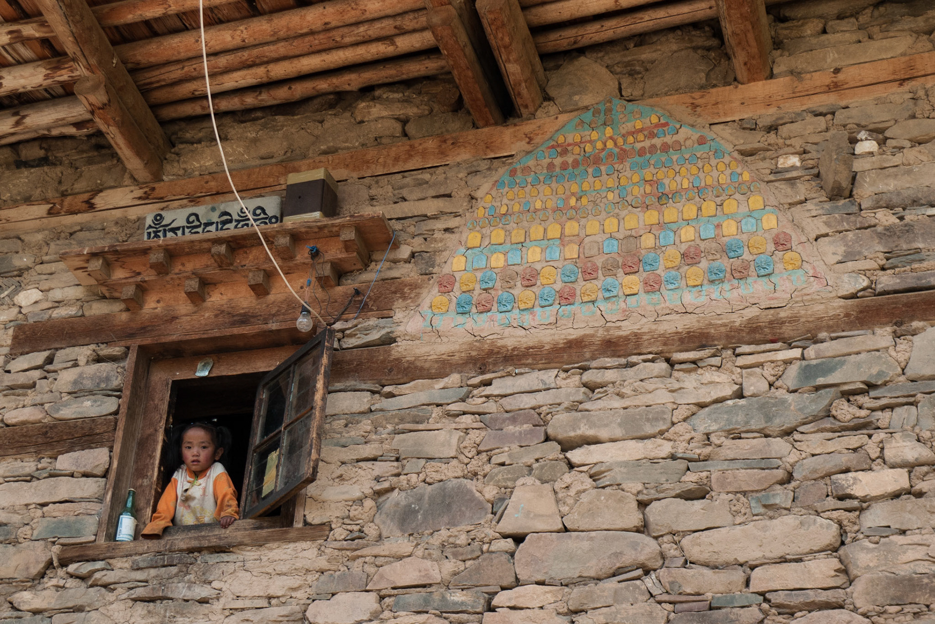 China, Eastern Tibet or Western Sichuan, also known as Kham, a young girl looks out of the window of her home.