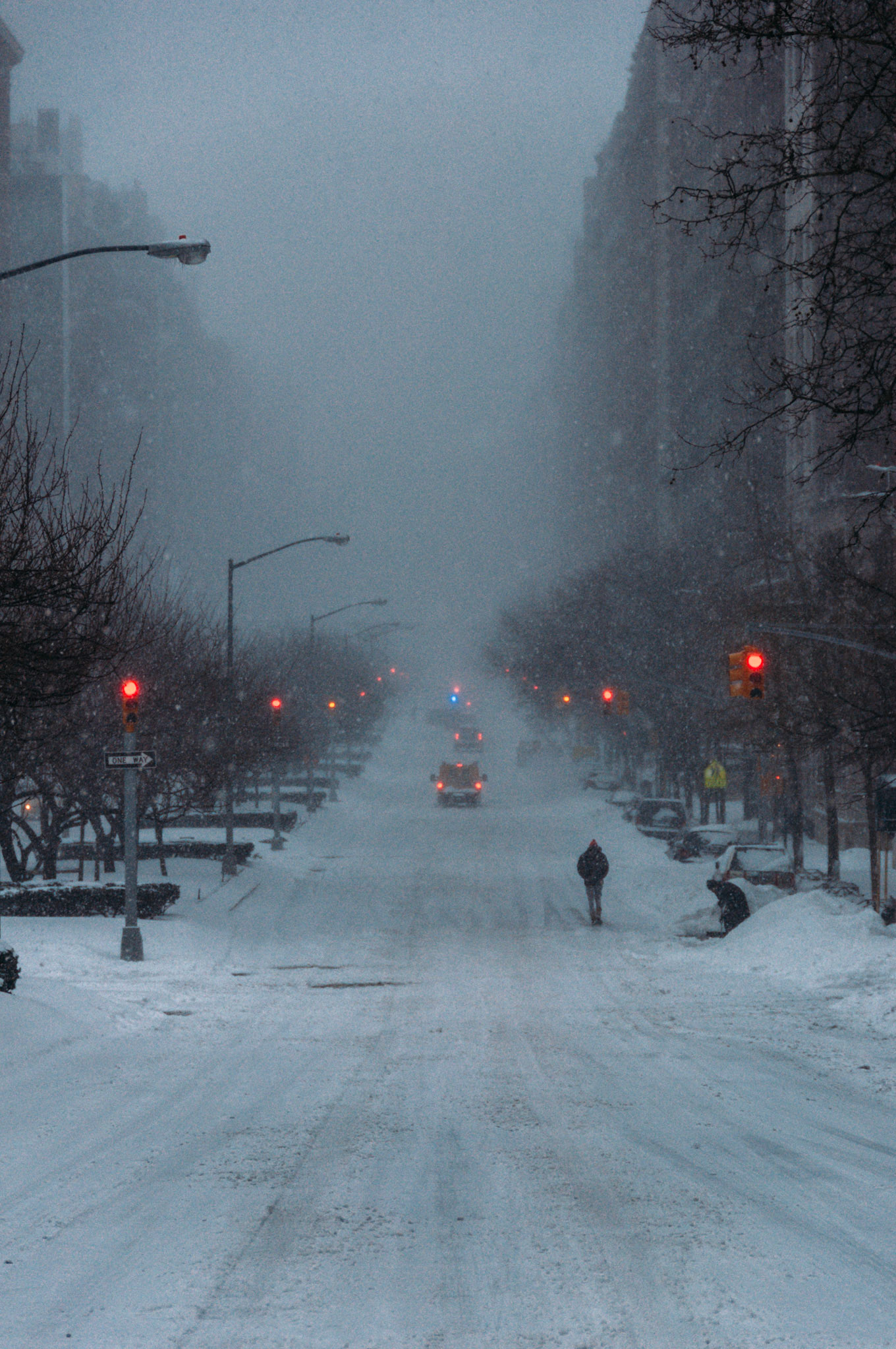 The southbound lanes of Park Avenue are covered with snow and visability is low. Police respond to an accident in the distance.