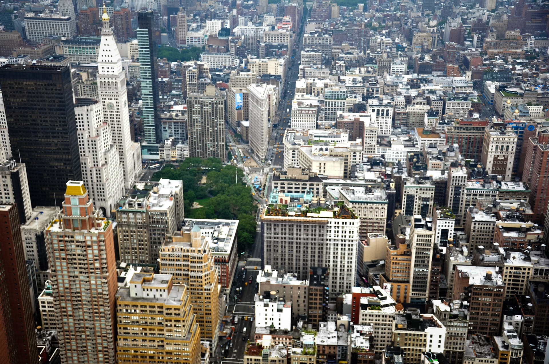 Fifth Avenue splits the photo of the Flatiron District in half. The historic Flatiron Building is on the left side of Fifth Avenue, where Broadway crosses over. Also to the left of Fifth Avenue is Madison Square Park, The Metropolitan Life Tower, Metropolitan Life North Building and the modern One Madison Avenue